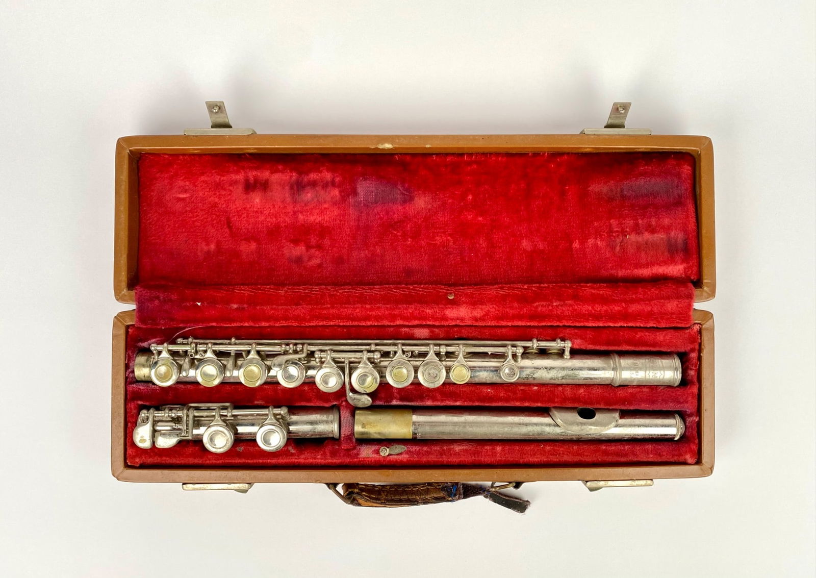 Bundy by Selmer Silver-Plated Student Flute with Case: A Bundy flute by Selmer with a silver-plated finish, stored in a hard case with red velvet lining. The flute exhibits heavy signs of wear and patina consistent with age and use. The hard case shows su