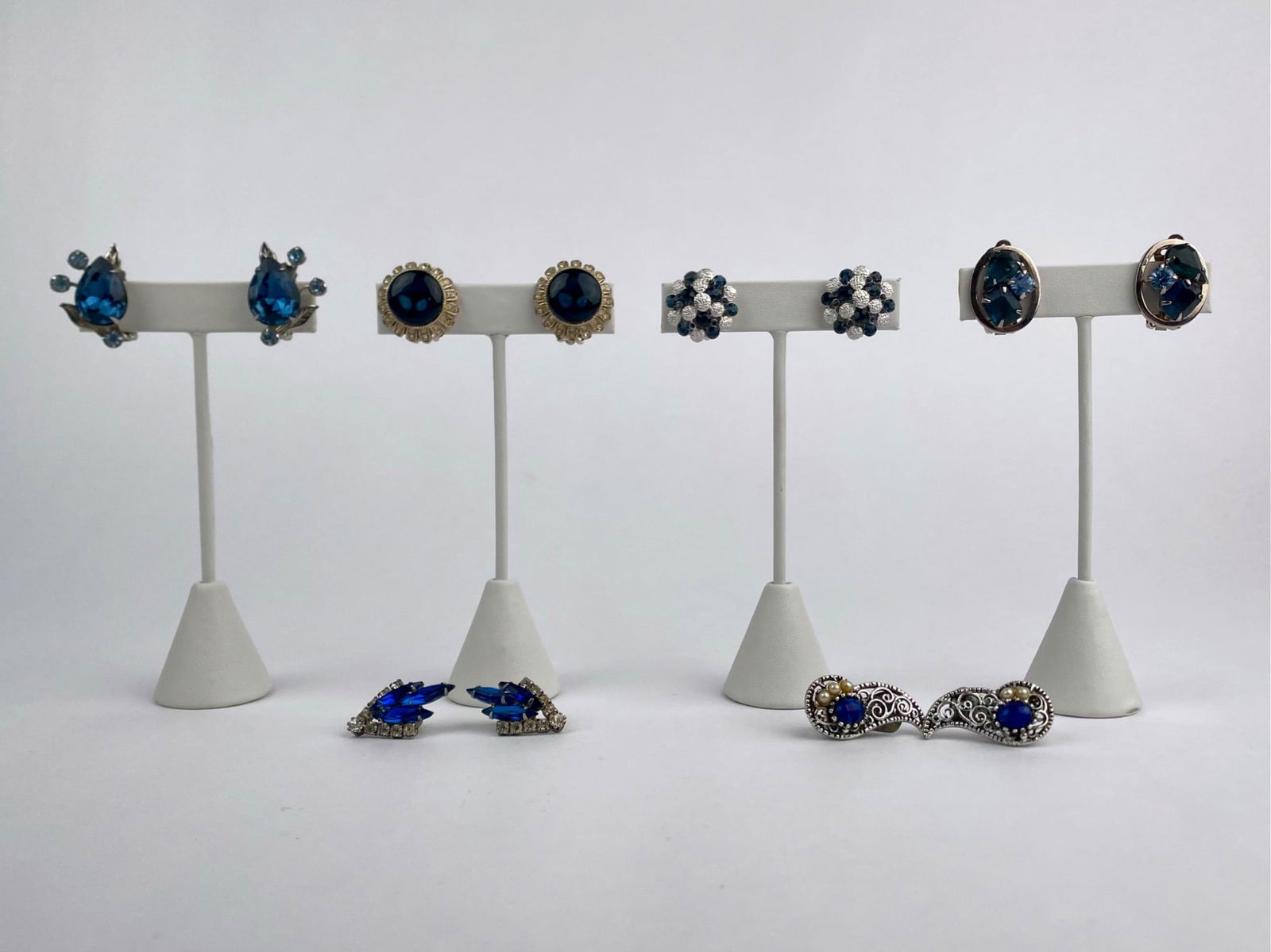 Group of eight pairs of vintage clip-on earrings featuring blue rhinestones in a variety of cuts and: Group of eight pairs of vintage clip-on earrings featuring blue rhinestones in a variety of cuts and settings. Designs include floral clusters, teardrop forms, navette arrangements and oval mounts in