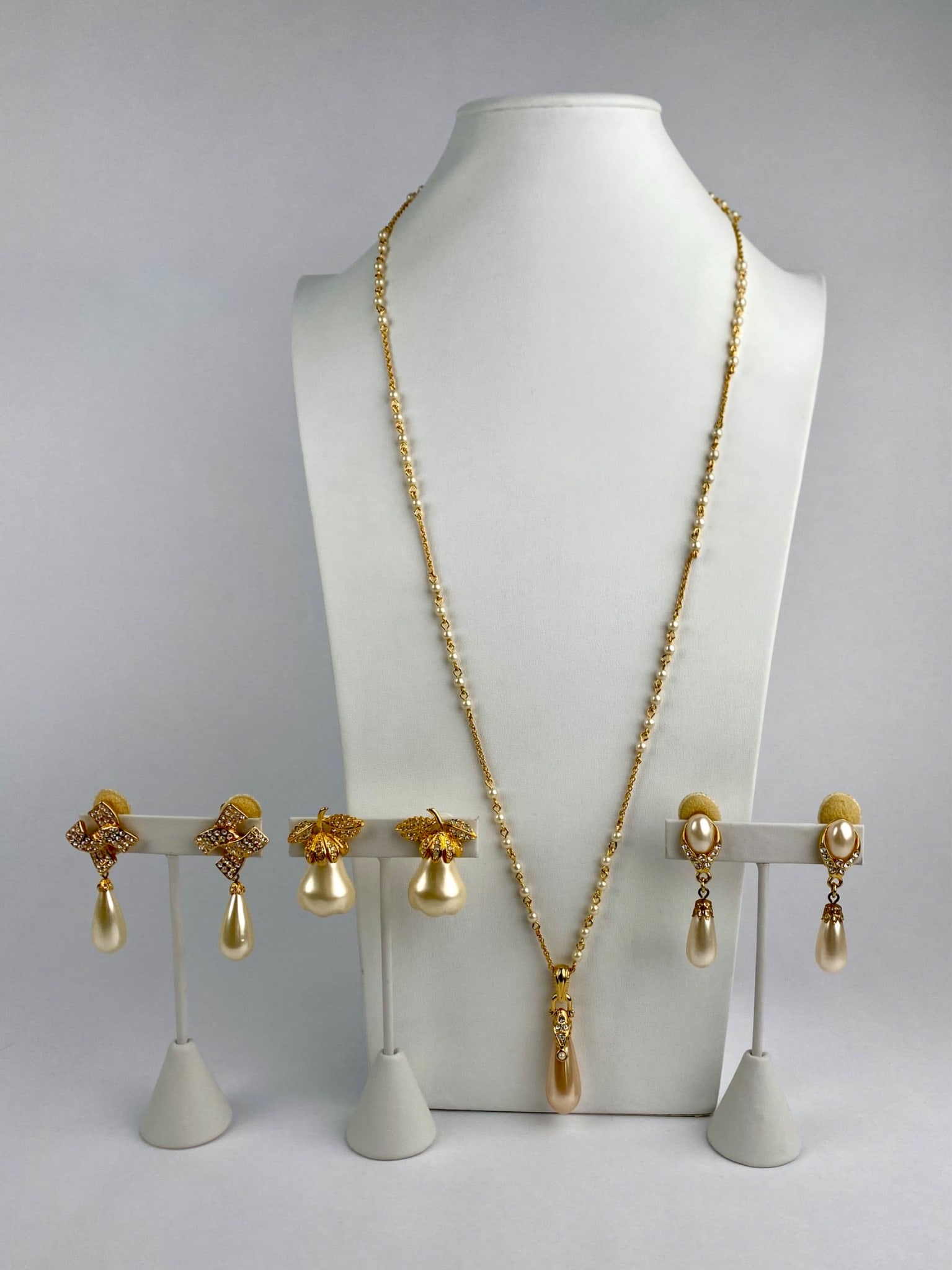 Signed Nolan Miller Faux Pearl Necklace & Three Pair KJL Earring Set: Coordinated designer costume jewelry set includes a signed Nolan Miller gold-tone necklace with faux pearl accents and teardrop pendant, accompanied by three pairs of Kenneth Jay Lane (KJL) clip-on ea