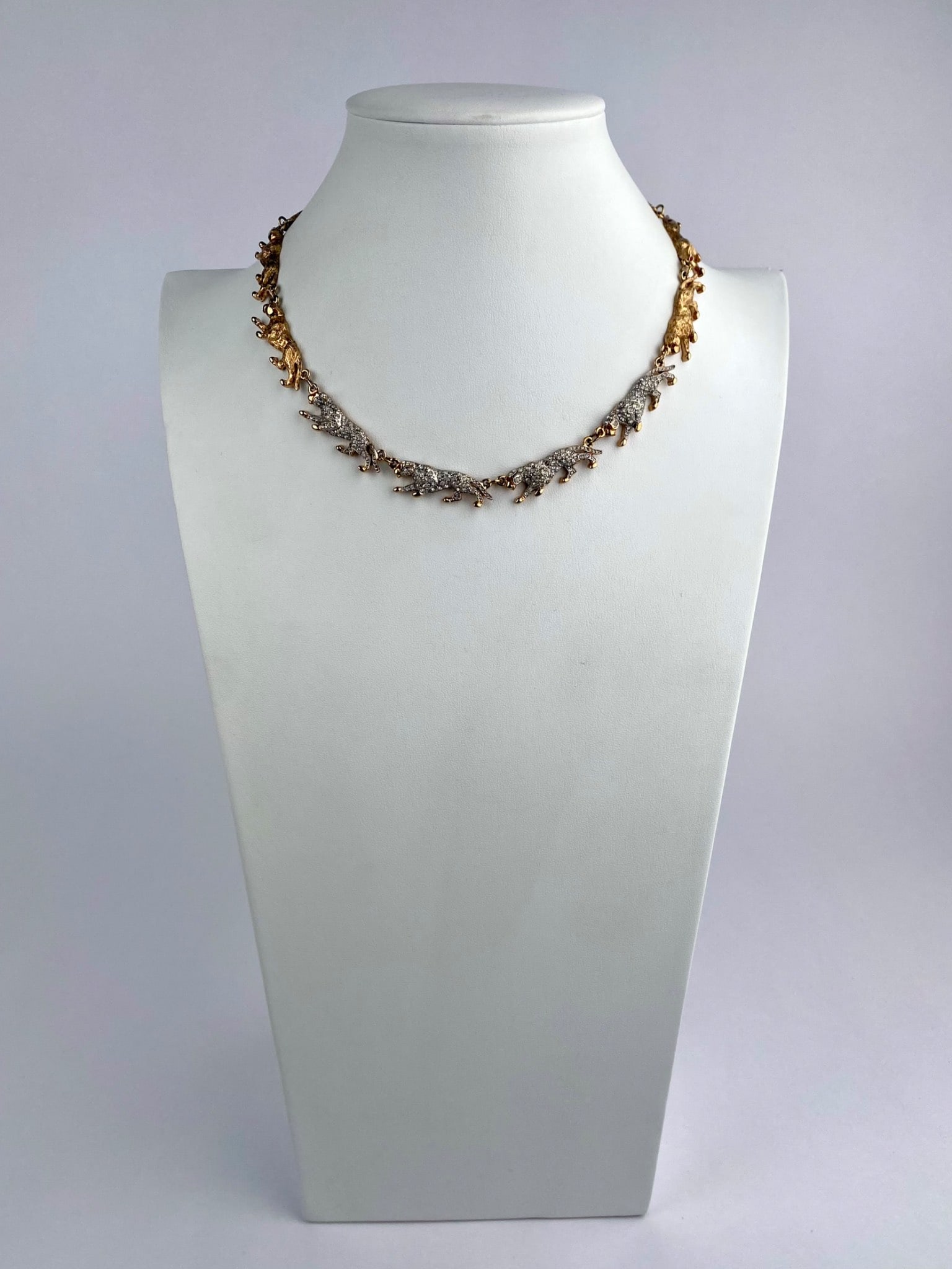 Gold-Tone Figural Leopard Necklace with Rhinestone Accents: Gold-tone necklace composed of articulated figural leopard links, with textured gold-tone forms and pave-set rhinestones examples. Figures feature small red stone eyes. The necklace is fitted with a l