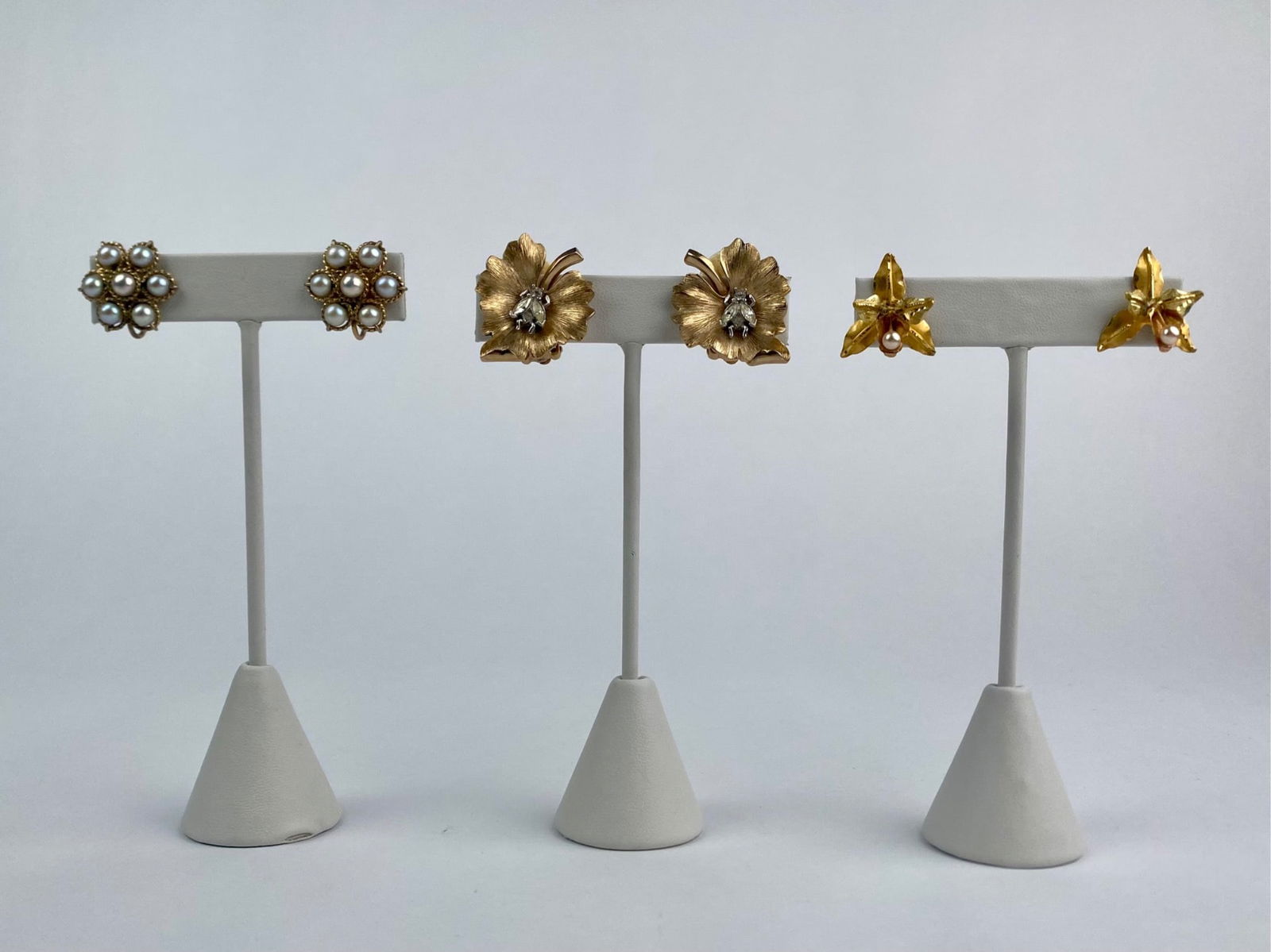 Group of three pairs of vintage gold-tone earrings in floral motifs. The set includes a pair of: Group of three pairs of vintage gold-tone earrings in floral motifs. The set includes a pair of pearl cluster earrings marked "JMS 1/20 12K Gold Filled," a pair of brushed gold-tone flower earrings wi
