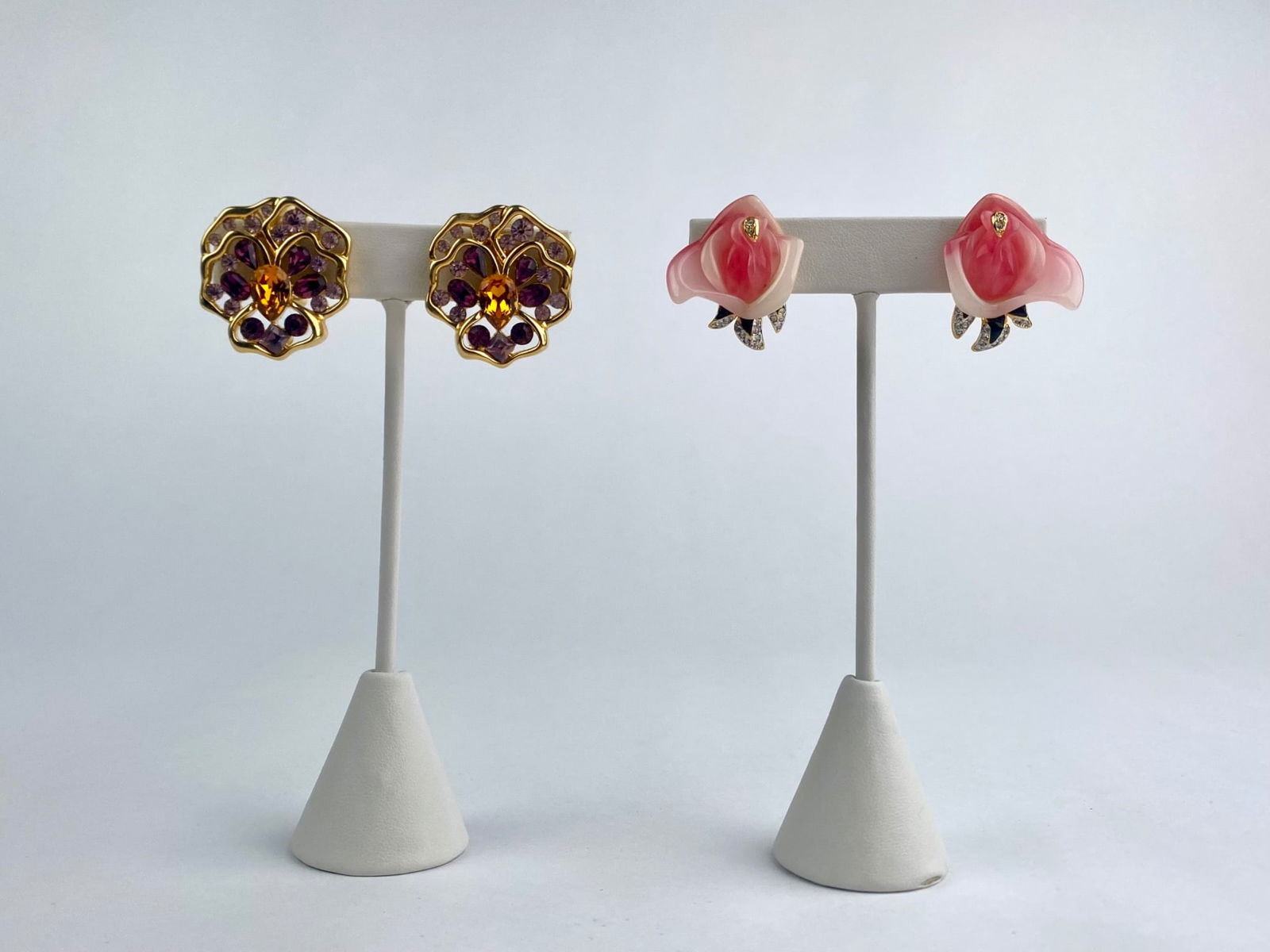 Set of two pairs of vintage designer clip-on earrings. The first pair features sculptural pink: Set of two pairs of vintage designer clip-on earrings. The first pair features sculptural pink molded resin rose-form earrings with gold-tone mounts, rhinestone accents and signed KJL (Kenneth Jay Lan