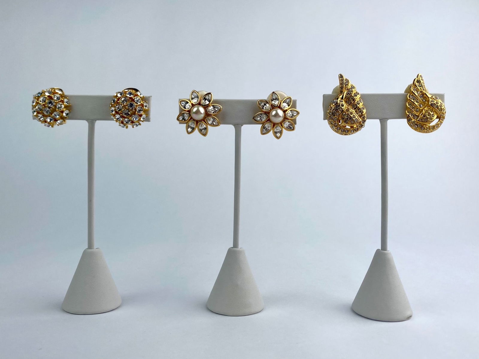 Lot includes three pairs of vintage gold-tone costume clip-on earrings by designers Nolan Miller and: Lot includes three pairs of vintage gold-tone costume clip-on earrings by designers Nolan Miller and Joan Rivers. The group features a domed pave rhinestone design, a floral motif with marquise-cut cl