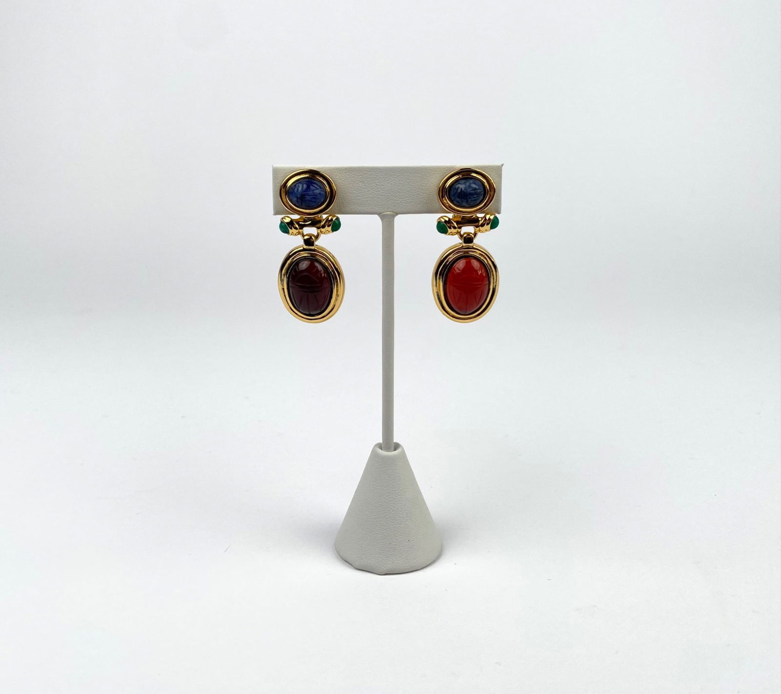 Gold-Tone Scarab Motif Clip-On Drop Earrings by Carolee: Gold-tone clip-on earrings featuring oval scarabs in blue, red, and green. Blue cabochons are set at the top with green accents, while red are engraved with a design and framed in gold. Clip-on backs