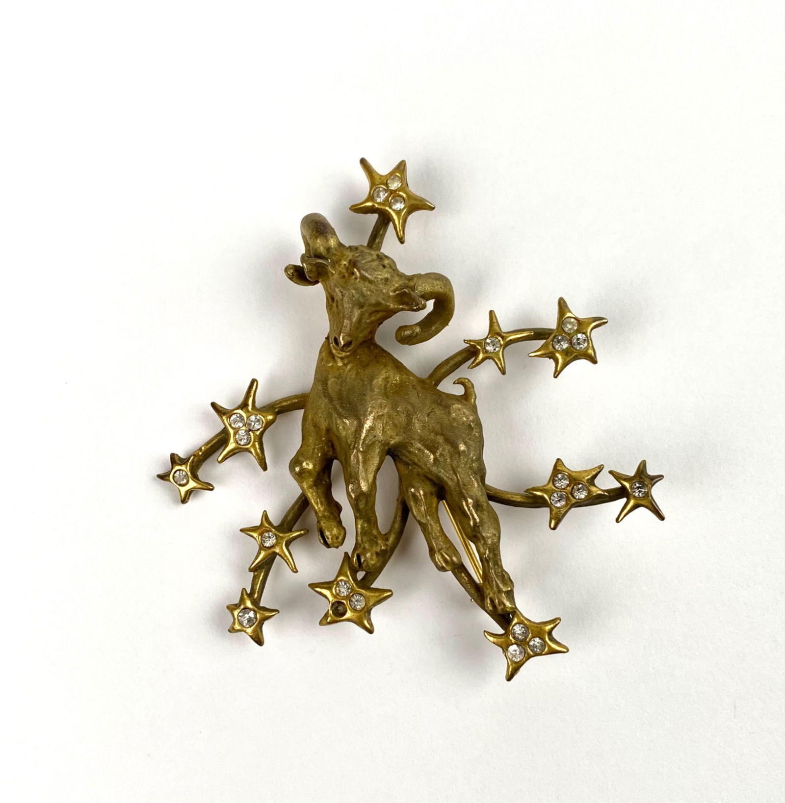 Vintage Vale Stevens Zodiac Capricorn Goat Brooch: Vintage gold-tone brooch marked ‘Vale Stevens’ featuring a goat motif surrounded by a stylized arrangement of stars, each inset with clear rhinestones. Shows intricate craftsmanship on both the fi