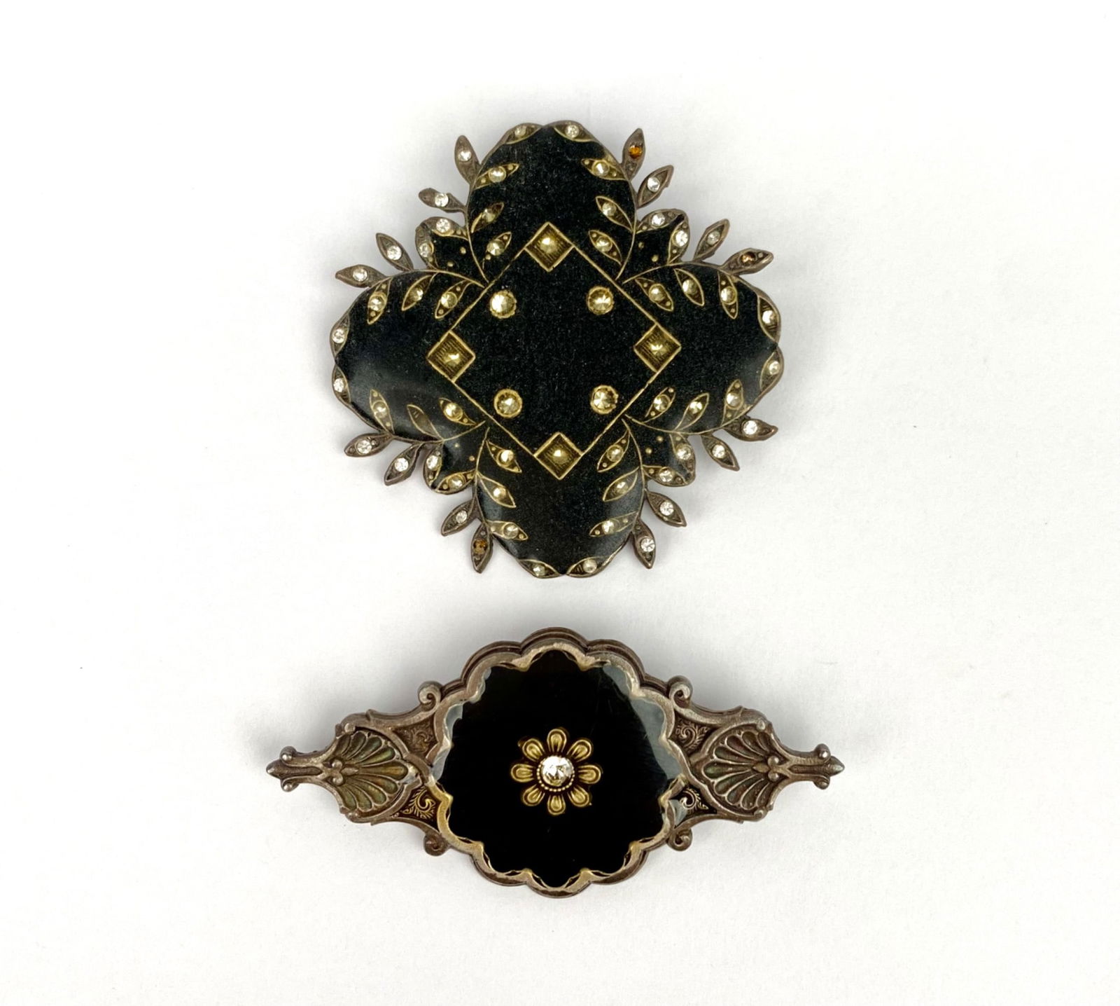 Pair of Catherine Popesco Brooches: Metal brooches designed by Catherine Popesco, made in France. Each brooch features dark enamel detailing and crystal accents, crafted in intricate patterns. Both display “Catherine Popesco” an