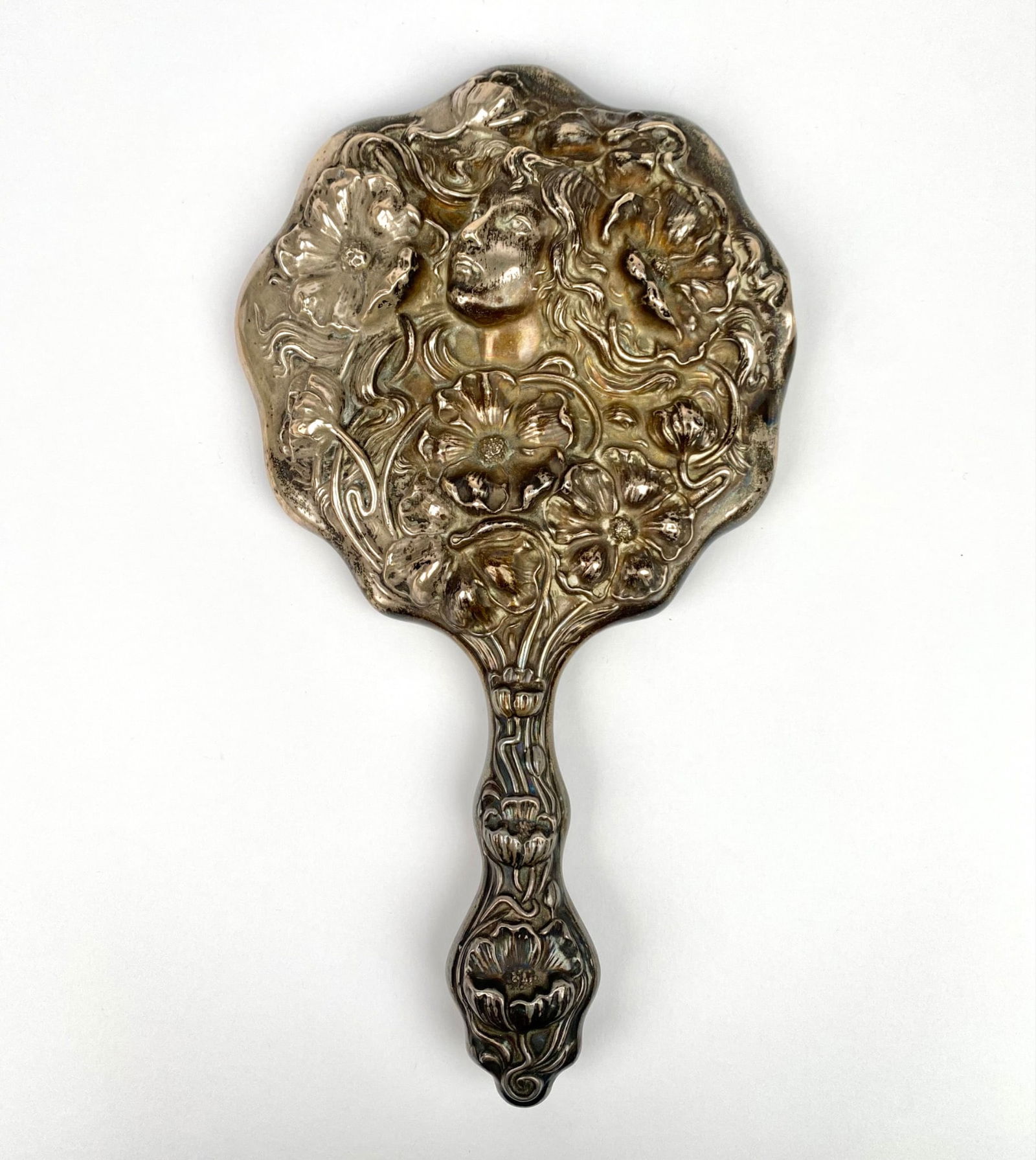 Sterling silver hand mirror featuring an ornate Art Nouveau-style design with floral motifs and a: Sterling silver hand mirror featuring an ornate Art Nouveau-style design with floral motifs and a woman’s face in high relief. Marked “Sterling 925” and patented August 12, 1902. Reflective
