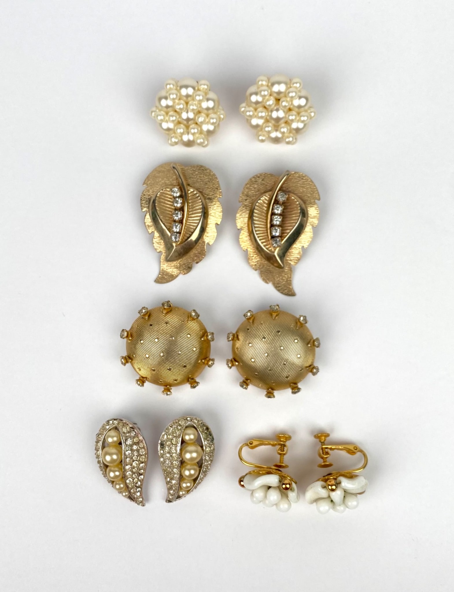 Five Pairs of Vintage Earrings Including Marvella & Hobe: Five pairs of earrings featuring metal, rhinestones, faux pearls, and plastic elements. Designs include floral motifs, textured finishes, and gold-tone details. Makers’ marks include ‘MARVELLA’