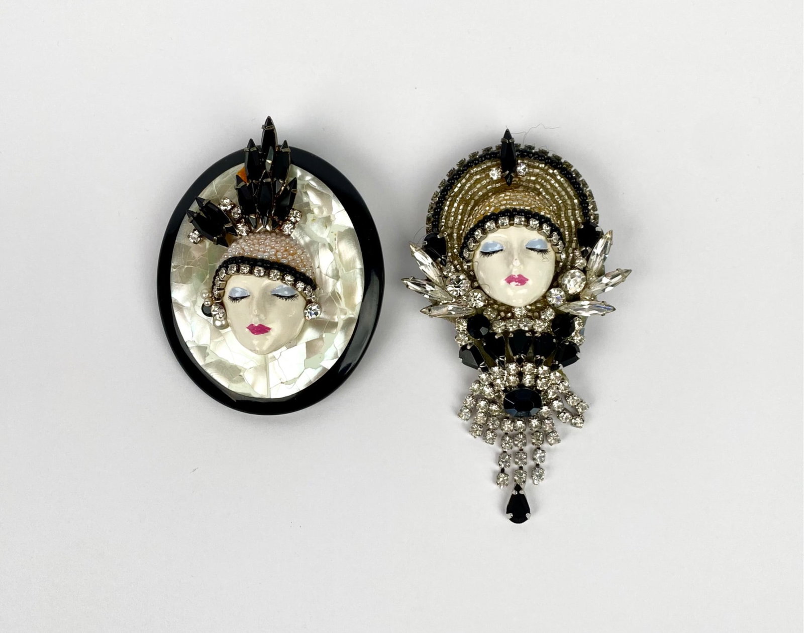 J. Solomon Art Deco-Style Flapper Face Brooch Set: Two brooches signed by J. Solomon. Each brooch features a detailed face motif accented with rhinestones, painted details, and intricate embellishments. Back of each brooch bears the artist’s signatu