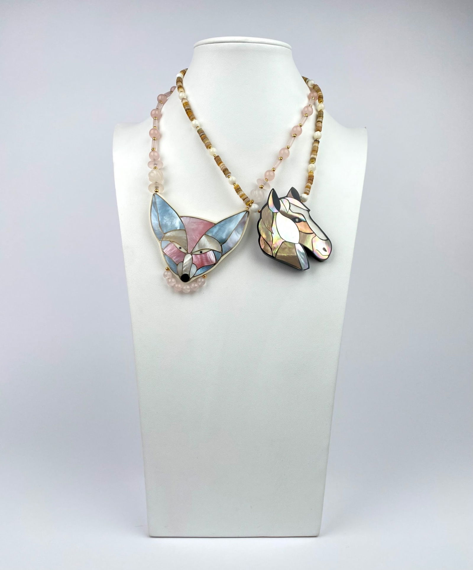Pair of Lee Sands Necklaces with Inlaid Fox & Horse Pendants: Pair of necklaces featuring two intricately inlaid pendants: a fox and a horse, crafted with mother-of-pearl and other materials. The chains consists of rose quartz, shell, and gold-tone beads, secure