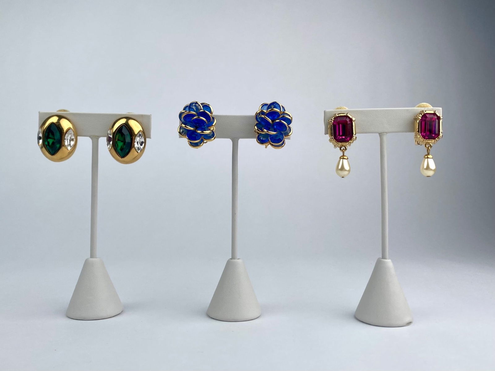 Group of Three Vintage Clip-On Costume Earrings with Rhinestones & Faux Pearls: Lot includes three pairs of vintage clip-on costume earrings. The group features one pair of gold-tone oval earrings set with green navette-cut stones and clear rhinestone accents, one pair of blue ca