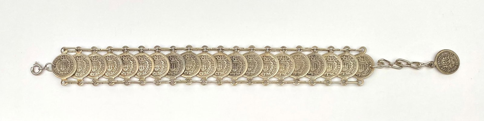 Silver-tone bracelet featuring San Marino medallions securely linked together in a repeating coin: Silver-tone bracelet featuring San Marino medallions securely linked together in a repeating coin motif design. The bracelet has a secure clasp and an additional medallion charm attached to the chain