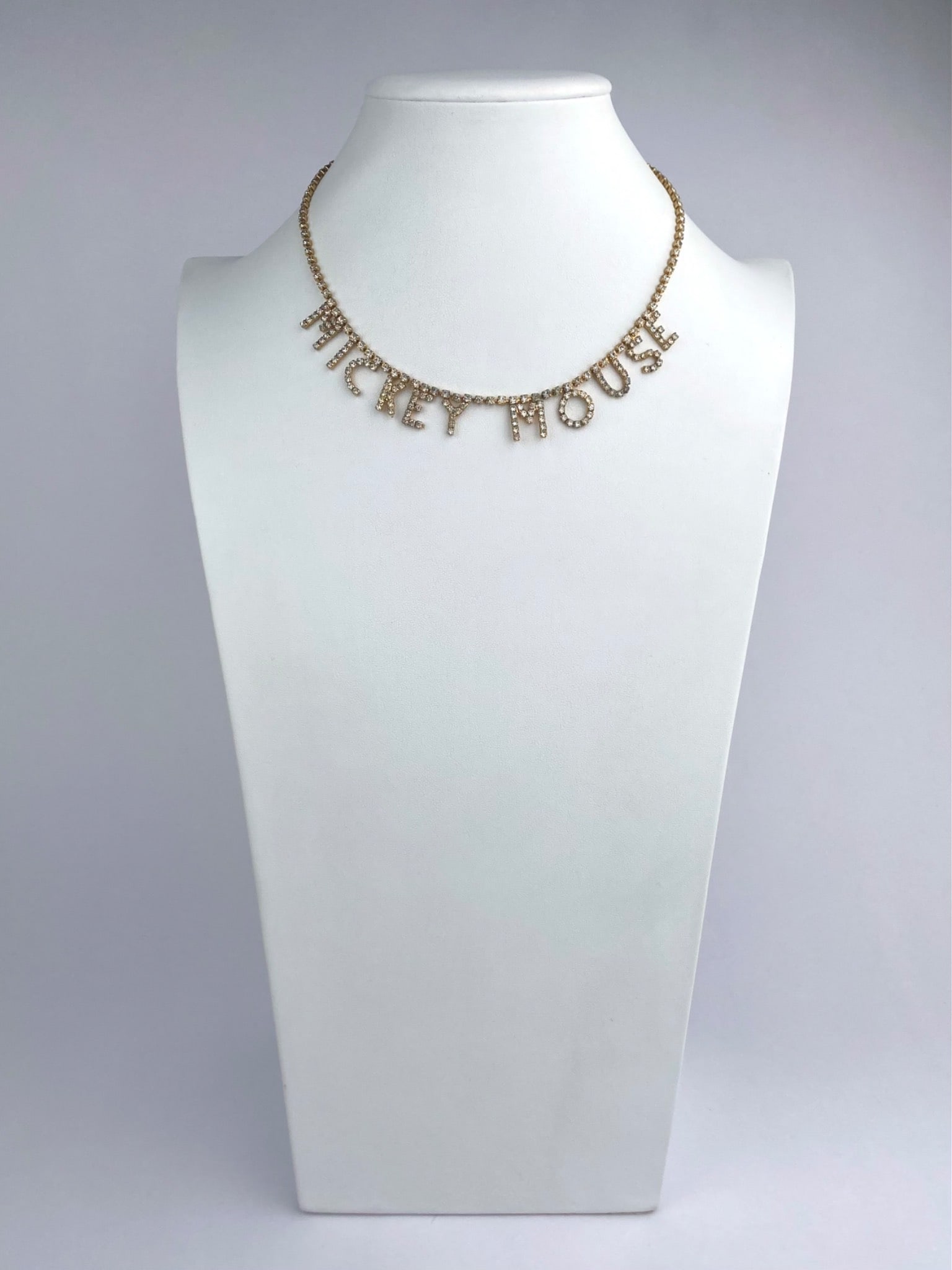 Disney Rhinestone ‘Mickey Mouse’ Name Necklace: Gold-tone rhinestone necklace featuring articulated letter charms spelling "MICKEY MOUSE," suspended from a matching rhinestone-set chain. The necklace is finished with a spring ring clasp and