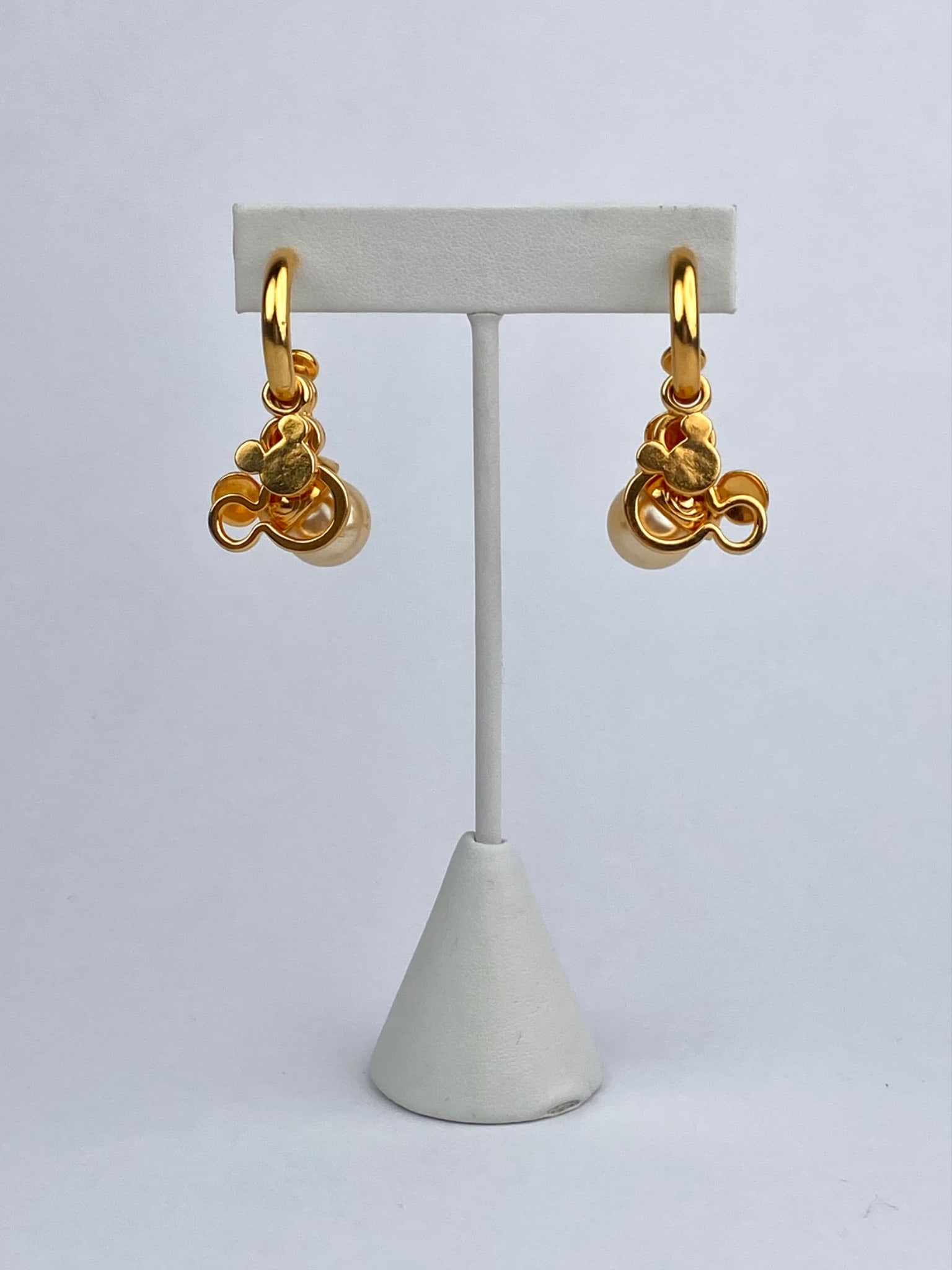 Pair of gold-tone hoop earrings featuring Disney Mickey Mouse charms accented with faux pearl drops.: Pair of gold-tone hoop earrings featuring Disney Mickey Mouse charms accented with faux pearl drops. Each earring is adorned with multiple dangling Mickey House head elements, including one with a sin