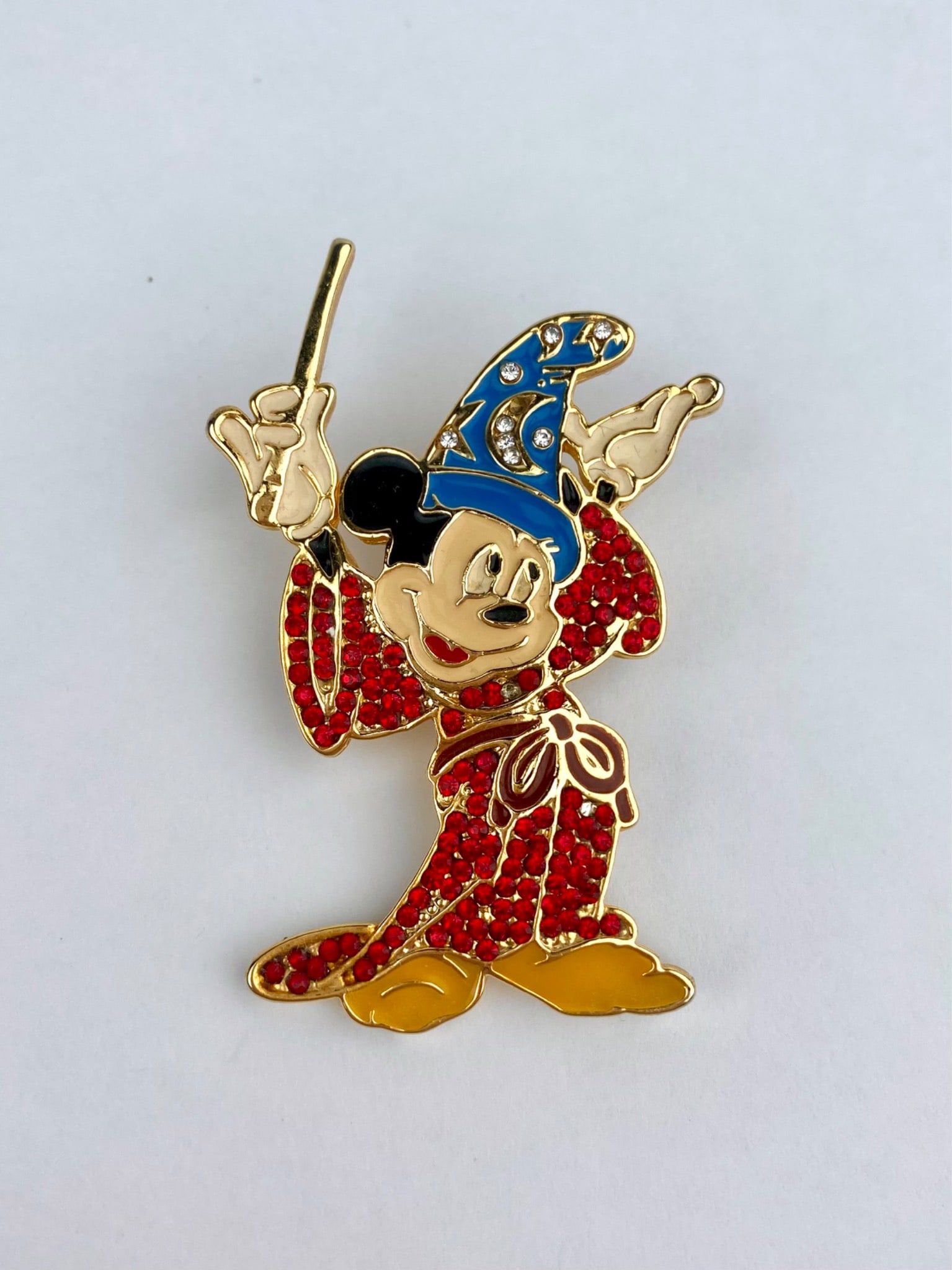 Disney character brooch depicting Sorcerer Mickey Mouse, executed in gold-tone metal with red: Disney character brooch depicting Sorcerer Mickey Mouse, executed in gold-tone metal with red pave-style rhinestones, blue enamel detailing, and clear crystal accents on the wizard's hat. The reverse