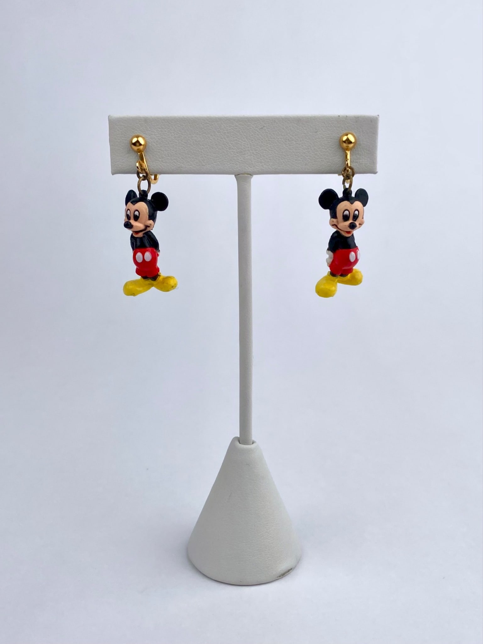 Pair of Disney figural clip-on earrings featuring three-dimensional Mickey Mouse charms in classic: Pair of Disney figural clip-on earrings featuring three-dimensional Mickey Mouse charms in classic black, red, yellow, and white coloring. The figures are suspended from gold-tone clip-back findings.