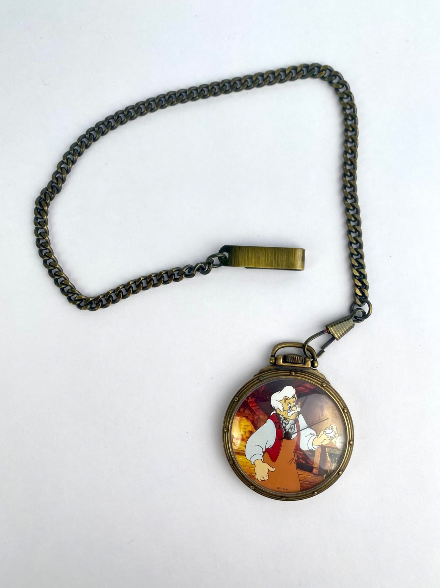 Disney Store Watch Collectors’ Club Series II Geppetto Pocket Watch, 792/7500: Round Disney pocket watch depicting Geppetto from Pinocchio, suspended from a curb-link chain with a matching fob style accent. The watch face is marked "Disney." The reverse case is stamped "DS 49,"