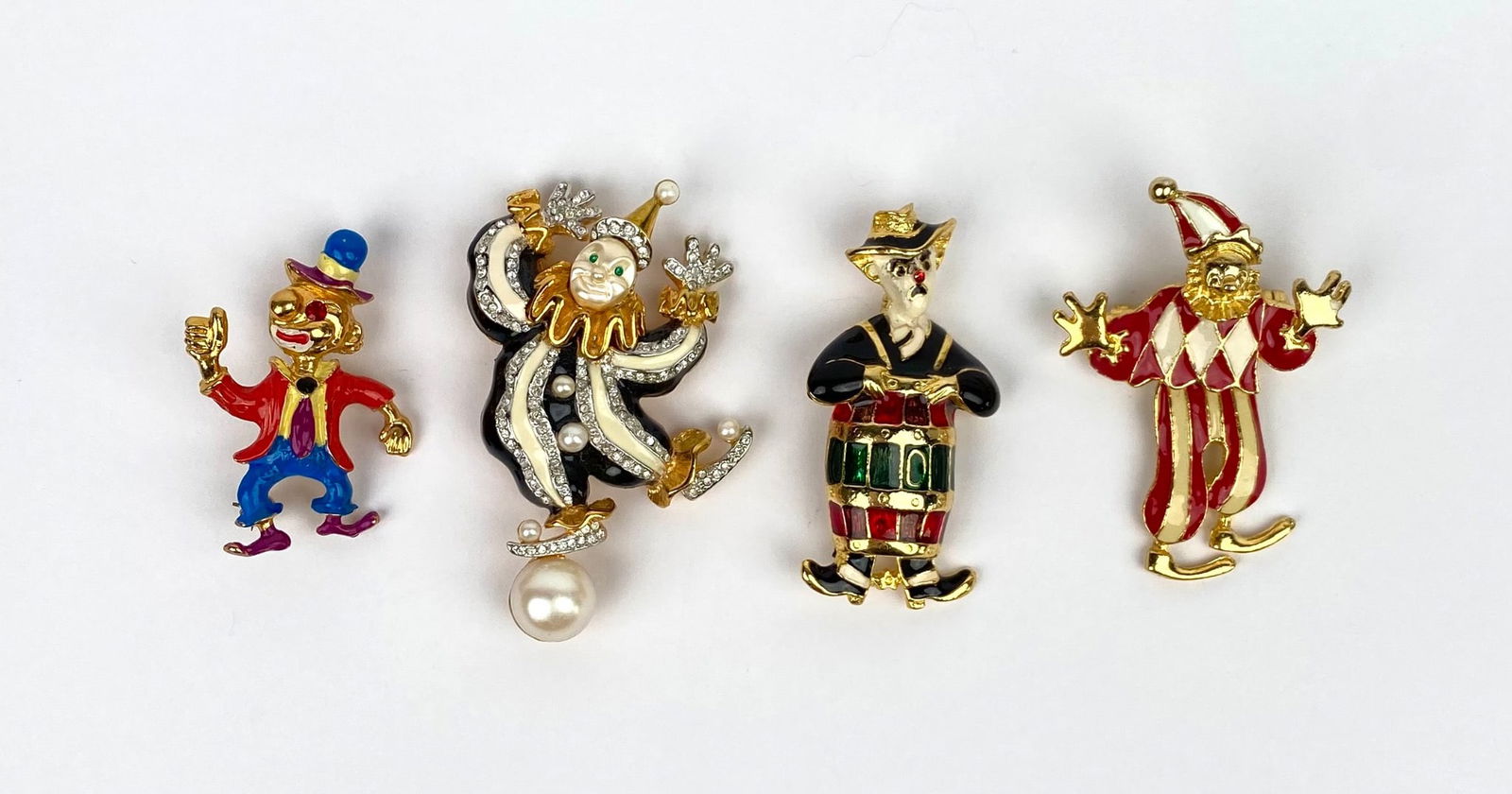 Set of Four Enamel & Gold-Tone Clown Brooches Including Kenneth Jay Lane: Four clown-themed brooches made from gold-tone metal with various enamel details. Each brooch features unique designs, including playful clown figures adorned with faux pearls, rhinestones, and