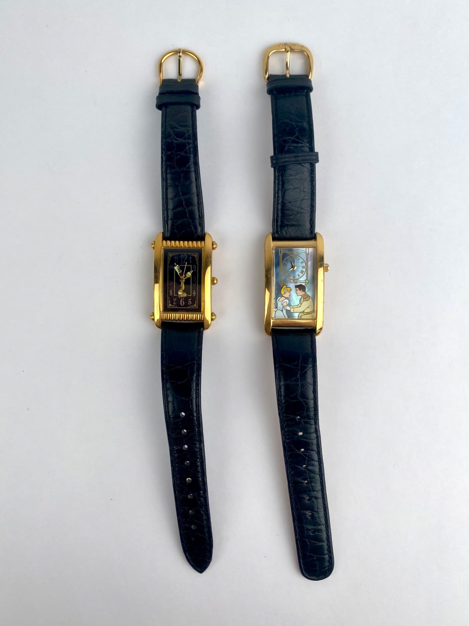 Lot includes two Disney Store Watch Collectors' Club limited edition rectangular wristwatches with: Lot includes two Disney Store Watch Collectors' Club limited edition rectangular wristwatches with gold-tone cases and black genuine leather straps. The first features Cinderella and Prince Charming b