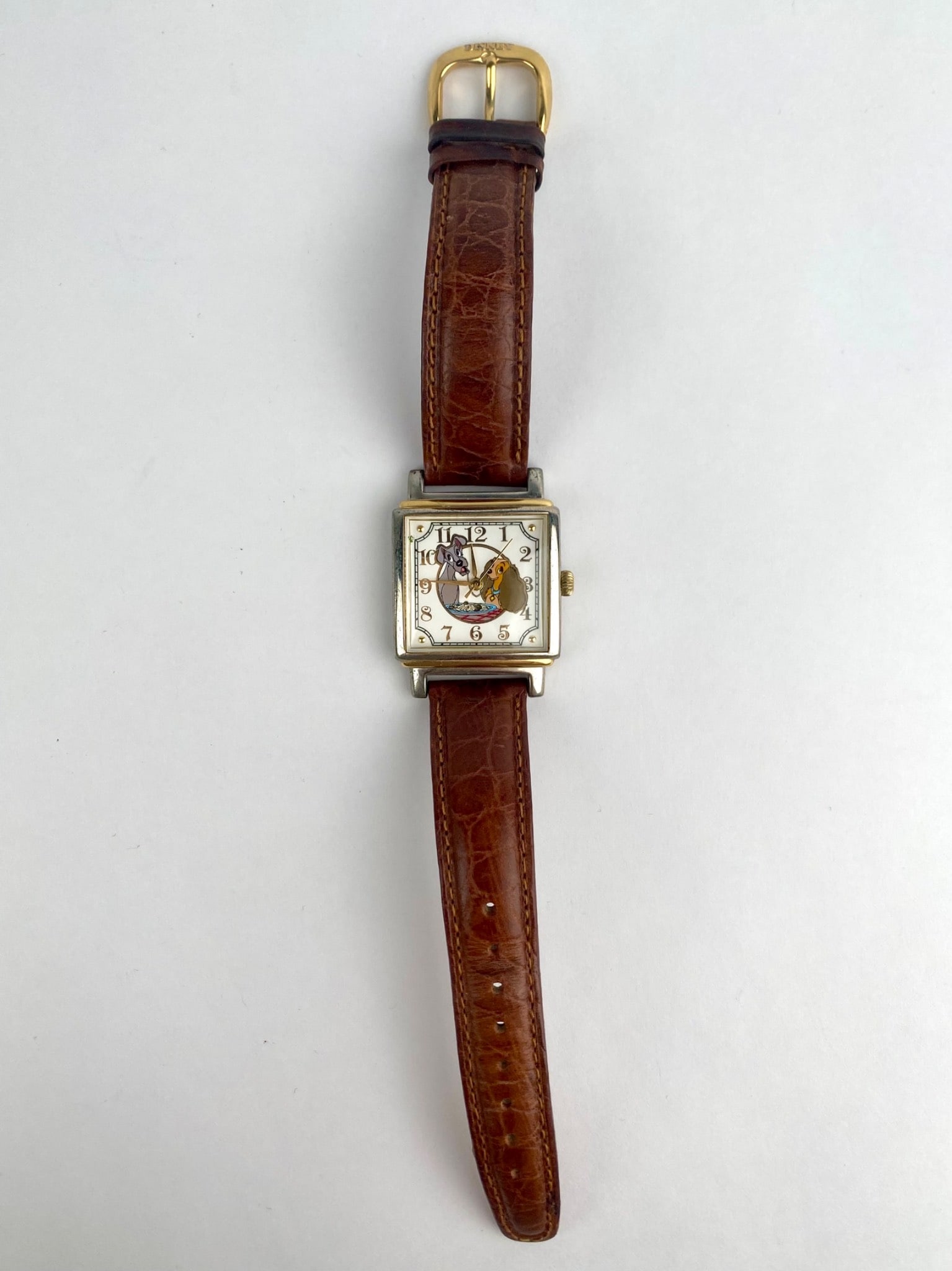 Disney Store Watch Collectors’ Club Series III ‘Lady and the Tramp’: Disney Store Watch Collectors' Club Series III wristwatch featuring a square two-tone case and a character dial depicting Lady and Tramp at the dinner table. The cream dial has stylized Arabic numeral