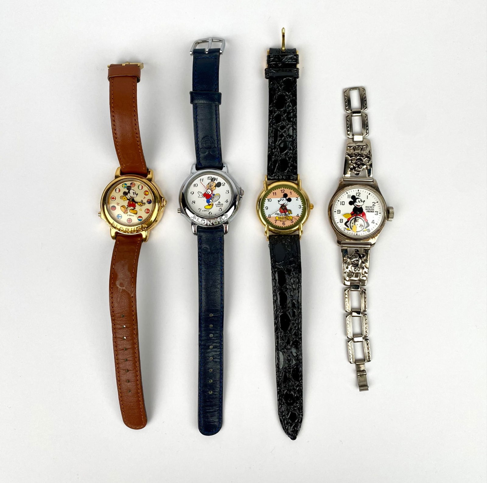 Four vintage Disney Mickey Mouse wristwatches. Each watch includes a unique character depiction on: Four vintage Disney Mickey Mouse wristwatches. Each watch includes a unique character depiction on the dial. Straps are made from materials including leather and metal; one is marked ‘Genuine Leathe