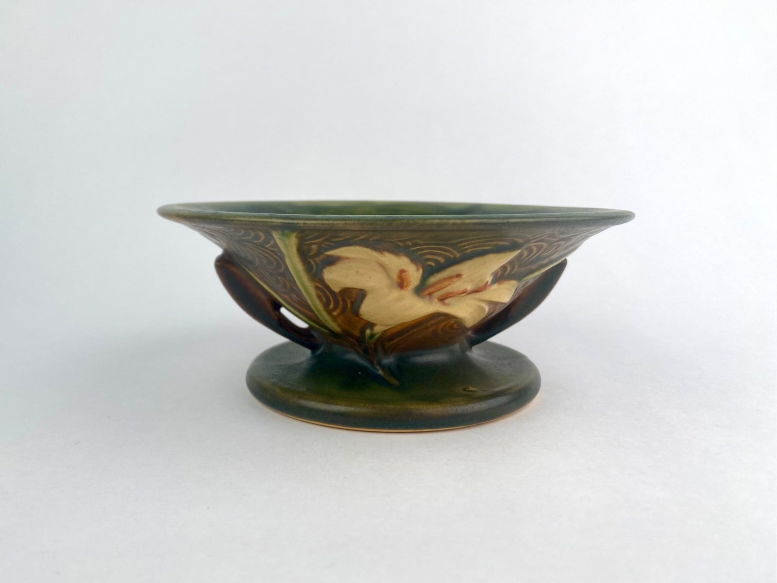 Roseville Pottery Water Lily pedestal bowl, model 473-6, produced in Roseville, Ohio. The piece: Roseville Pottery Water Lily pedestal bowl, model 473-6, produced in Roseville, Ohio. The piece features molded water lily blossoms and foliage in relief around the body with incised swirling