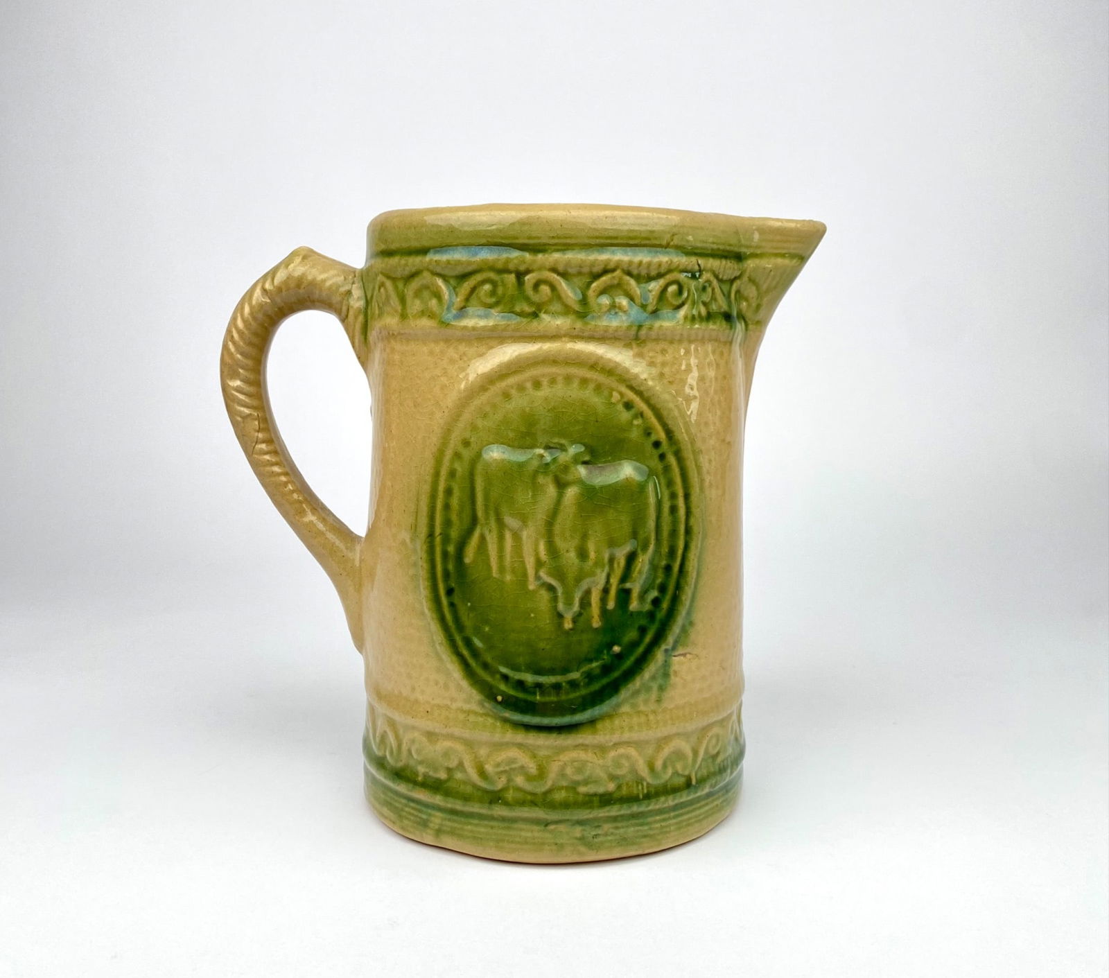 Hull Pottery pitcher featuring a relief cow motif in an oval medallion on both sides, accented with (1 of 7)