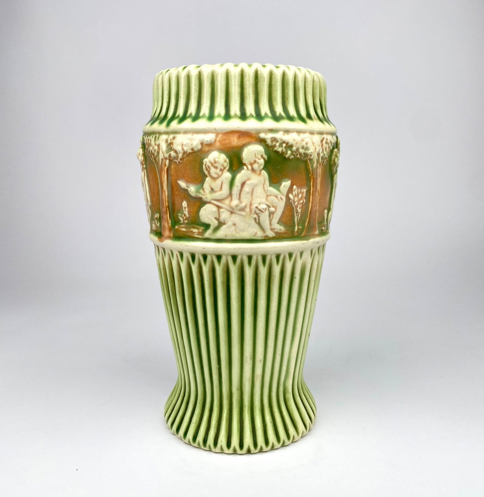 Green and white ceramic Donatello vase featuring intricate figural relief designs depicting children (1 of 6)