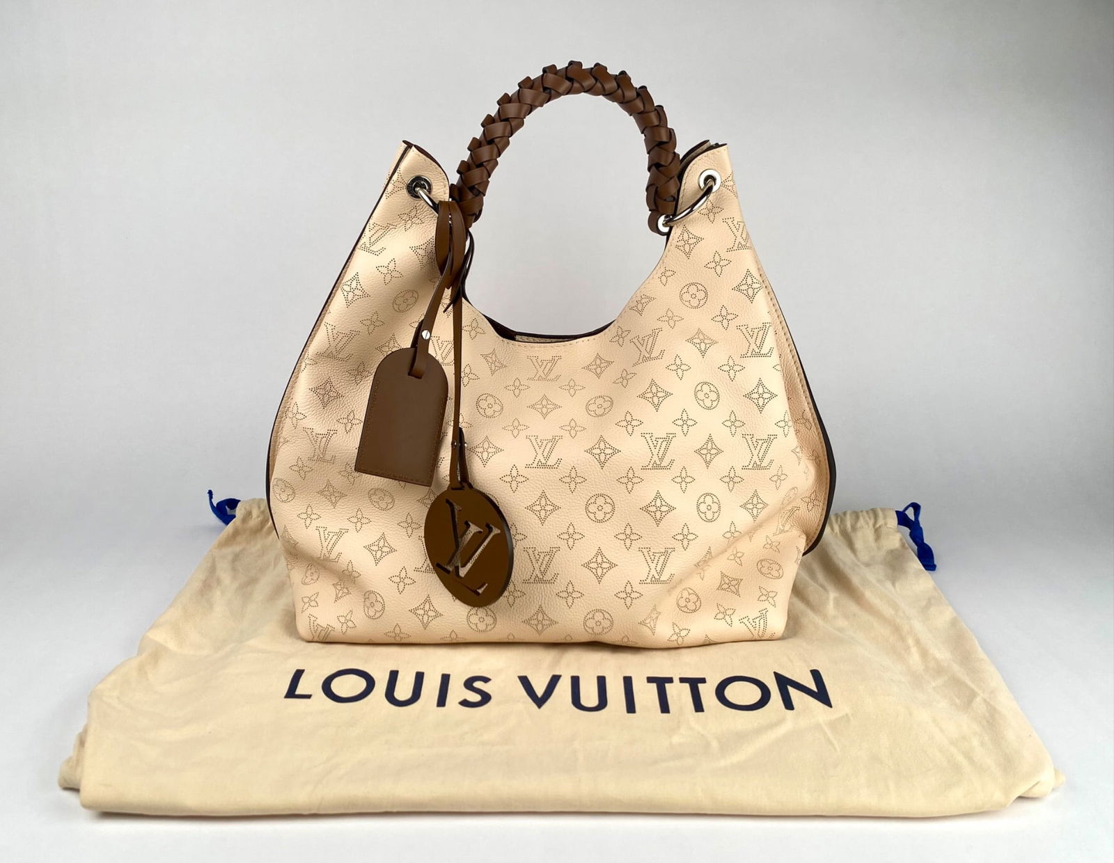 Louis Vuitton Monogram Mahina Leather Hobo handbag featuring a perforated monogram pattern on beige: Louis Vuitton Monogram Mahina Leather Hobo handbag featuring a perforated monogram pattern on beige grain leather with brown leather braided handle. Includes a leather luggage tag and oversized Louis
