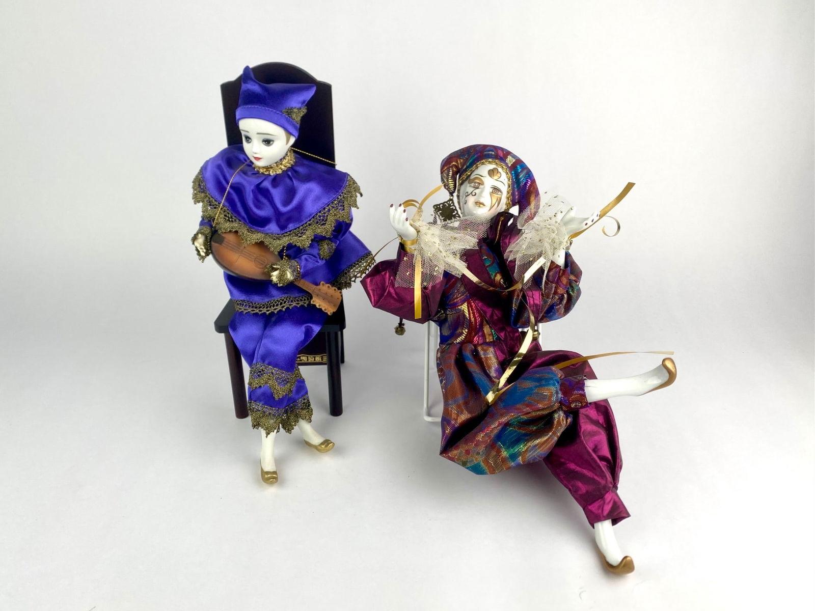Hakodate Orgel Meijikan Musical Doll & Porcelain Jester Figure: Lot includes two decorative theatrical-style figures. The first is a musical automaton doll produced by Hakodate Orgel Meijikan of Japan, seated on a wooden chair that houses a wind-up music box mecha