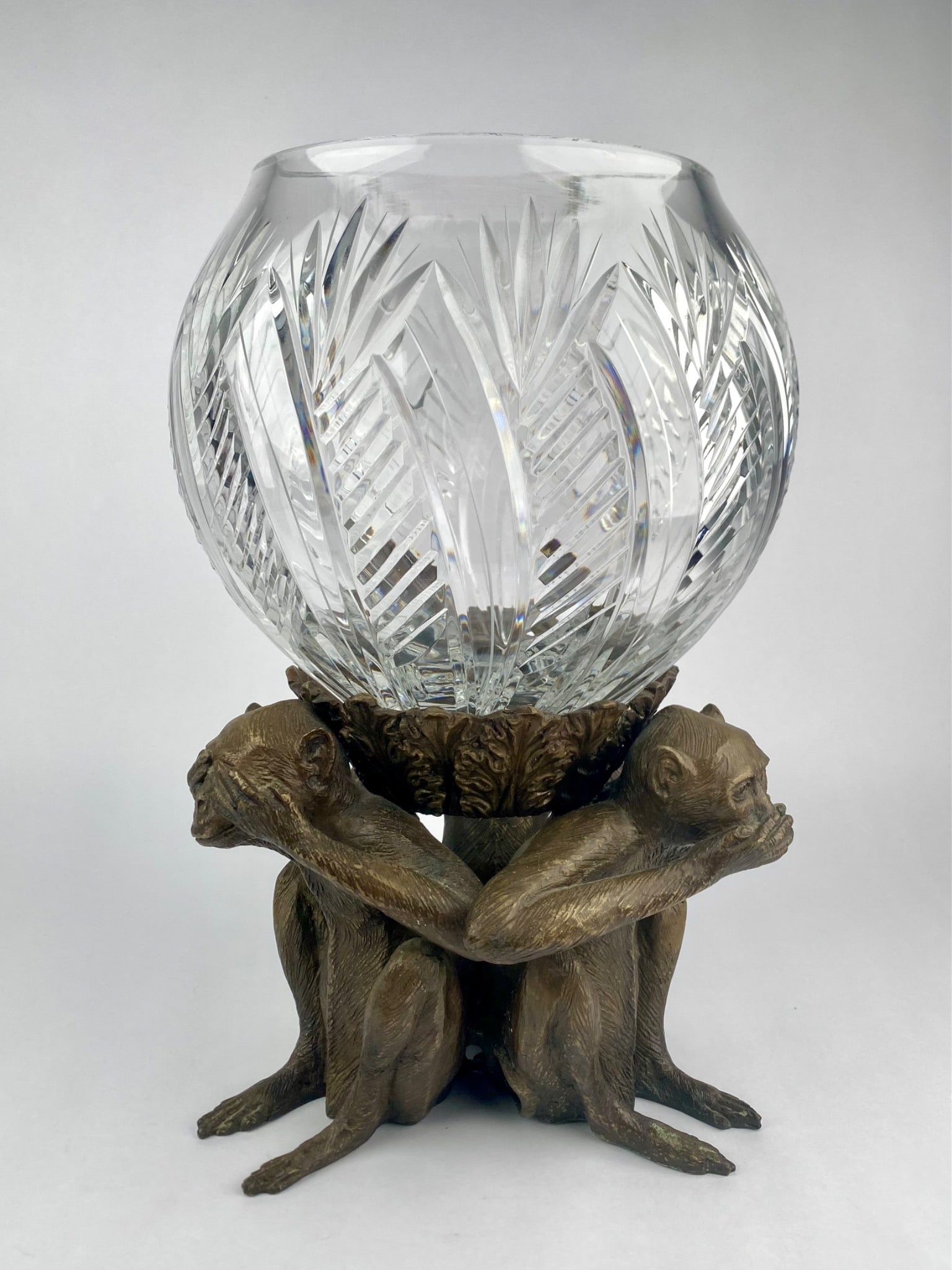 Decorative bowl featuring a sculptural base modeled as the "Three Wise Monkeys" motif cast in: Decorative bowl featuring a sculptural base modeled as the "Three Wise Monkeys" motif cast in bronze-tone metal. The monkeys sit back-to-back supporting a removable cut crystal bowl with geometric sta