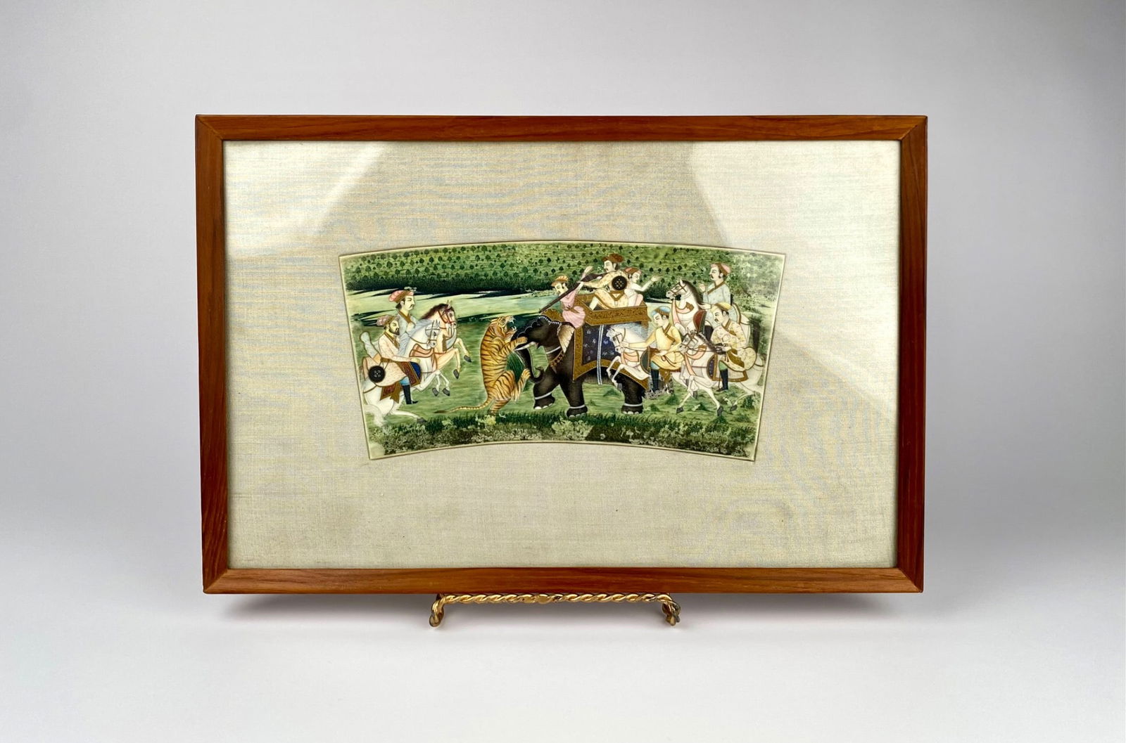 Framed Mughal-Style Tiger Hunt Miniature Painting: Framed Indian miniature painting depicting a detailed hunting scene on a rectangular ceramic panel. The artwork features hunters on horseback and an elephant in pursuit of a tiger amidst a lush
