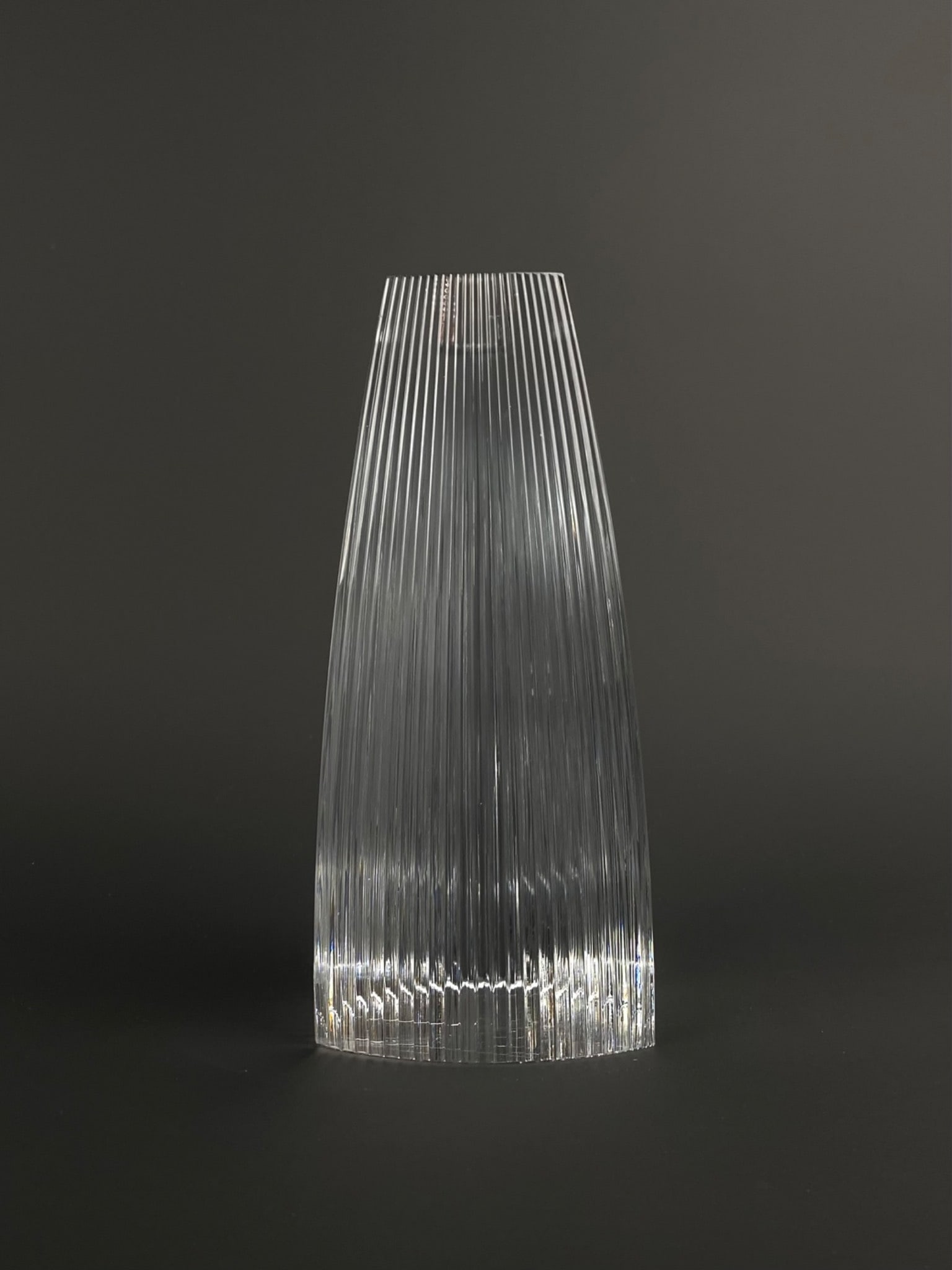 Tiffany & Co. clear crystal candlestick holder featuring a modern triangular form with softly: Tiffany & Co. clear crystal candlestick holder featuring a modern triangular form with softly rounded corners and a finely ribbed vertical fluting throughout the body. The holder tapers upward to a ci