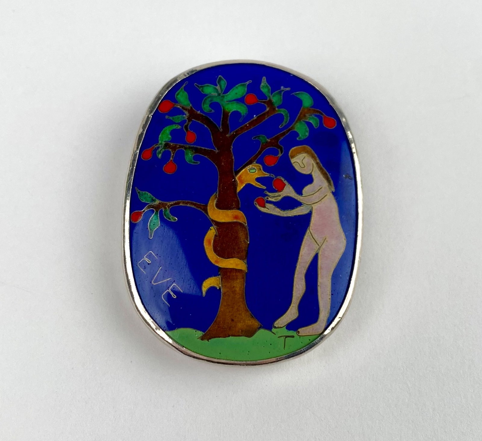 Silver & Enamel Eve & The Serpent Brooch/Pendant: Silver brooch featuring an enamel depiction of Eve with the serpent wrapped around an apple tree under a cobalt blue background. The brooch has a bar pin fitting and loop attachment on the reverse sid