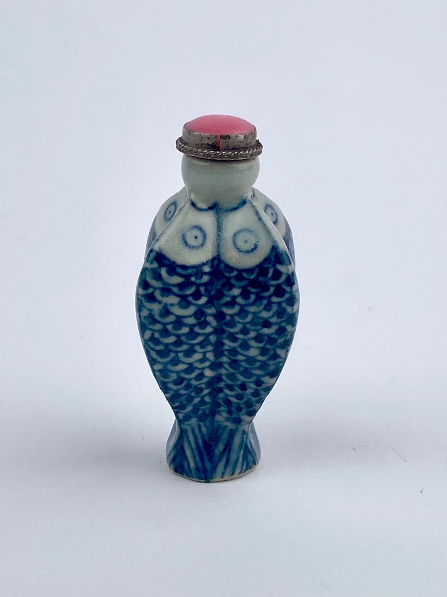 Chinese Blue & White Fish-Form Porcelain Snuff Bottle with Pink Glass Stopper: Chinese porcelain snuff bottle modeled in the form of a stylized fish, decorated in underglaze blue and white with repeating scale patterns and circular eye motifs. The bottle features a flattened bod