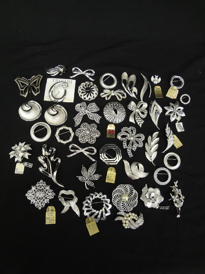 (40) Trifari Silvertone Brooches Original Tags: (40) Trifari Silvertone Brooches Original Tags: A large group of original Trifari Costue jewelry brooches. Many have their original tags. All shapes, sizes including bows, hearts, flowers, some with r