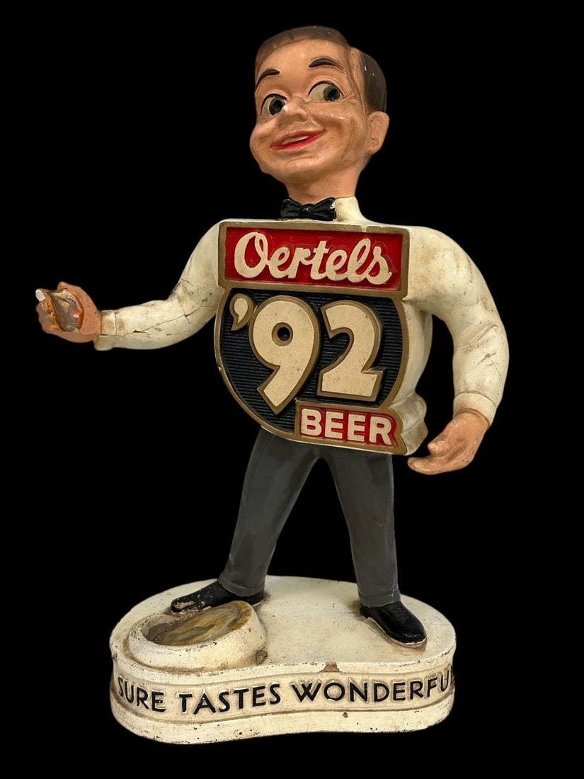 Oertel's Chalkware Advertising Sculpture: Oertel's Chalkware Advertising Sculpture: "Sure Tastes Wonderful" Missing the bottle. Measures 16.25" tall. Damage to one arm, chips on base.