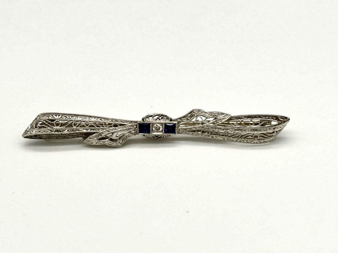 Filigreed Millgrained 14k White Gold, Diamond & Synthetic Sapphire Art Deco Bar Brooch: Filigreed Millgrained 14k White Gold, Diamond & Synthetic Sapphire Art Deco Bar Brooch: Set in 14k white gold with (1) old European cut natural diamond .05 carats, color G, clarity VS2. Set in 14k whi