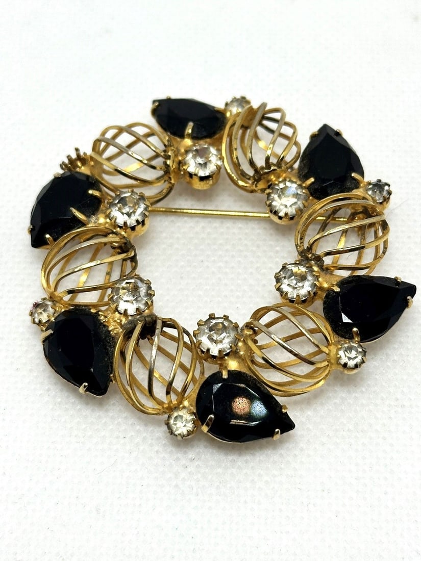 Hattie Carnegie Gold Tone Brooch: Hattie Carnegie Gold Tone Brooch: In black and clear rhinestones. Measures 2.25".