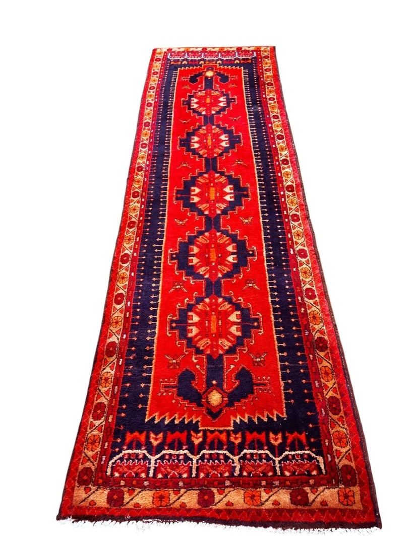 Persian Style Floor Rug Made In Iran: Persian Style Floor Rug Made In Iran is wool and measures 13 feet 6 inches in length and 3 feet, 9 inches wide. The rug has vibrant colors, and an attached label indicates the rug is hand crafted.
