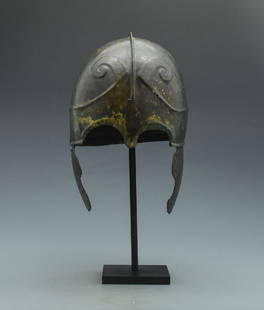 RARE GREEK CHALCIDIAN HELMET WITH HORNS OF ZEUS AMUN: An importnat bronze helmet formed from two curved segments each with a flared rim, nasal, raised panels to the upper section of the bowl, repousse ridge forming curved brows; integral cheek-plate to e