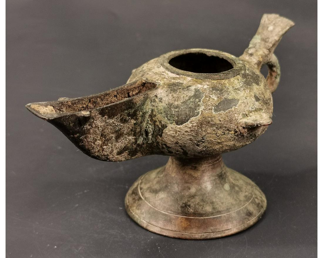 BYZANTINE BRONZE OIL LAMP ON STAND: Ca.500 AD.A bronze Piriform Lamp with broad nozzle, ovoid base, discus with flat hinged lid handle to the rear, tall conical base. Good Condition; intact; Size: 130x70mm;5.12x2.76in; 155gr; Provenance