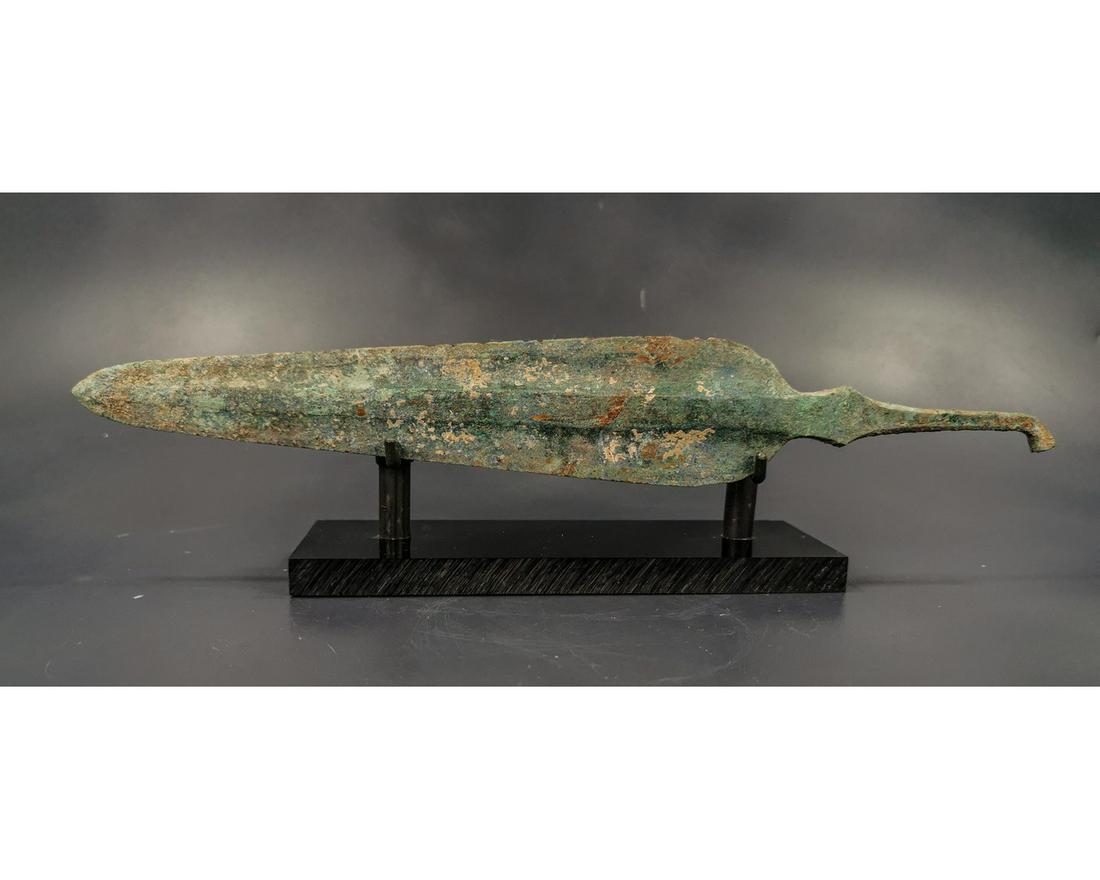 ANCIENT GREEK ARCHAIC PERIOD BRONZE SPEAR: Ca. 1600 - 1200 BC A bronze spear featuring an ovate blade with rectangular-sectioned midrib and gently curved shoulders and flaring tang. Including a custom made stand; 325mm; 12.8in; 290gr;From an i