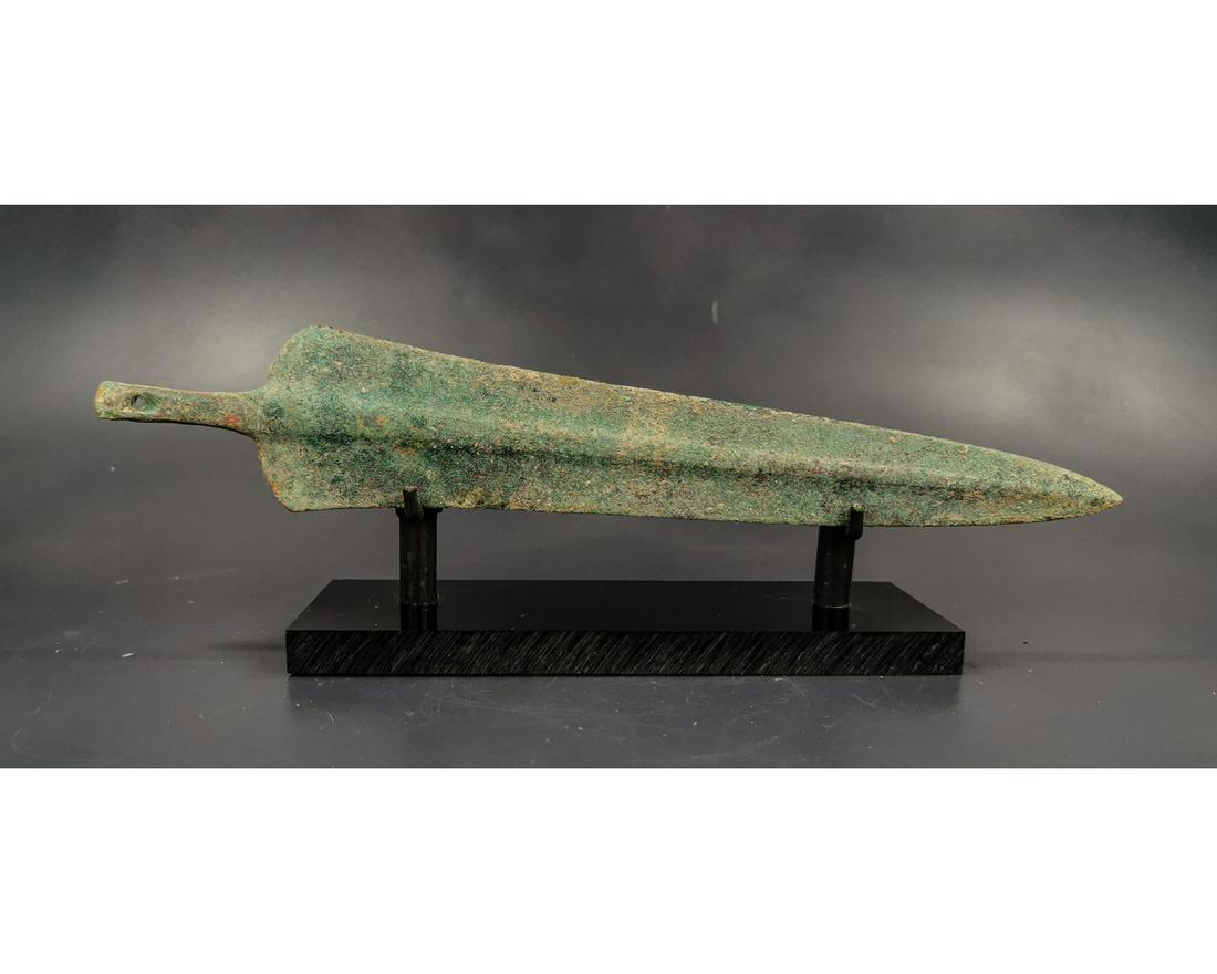 GREEK ARCHAIC SWORD BLADE: Ca. 1600 - 1000 BC. Greek Archaic period sword blade. A large and well-formed bronze blade that rises in the center in a very gentle ridge and flattens out at twin sharp edges. A sturdy tang ending in