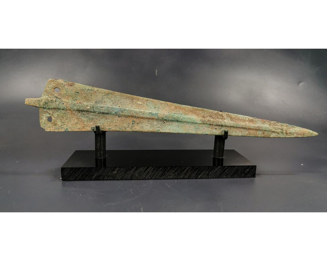 GREEK ARCHAIC PERIOD SWORD BLADE: Ca. 1600 - 1200 BC. Greek Archaic period Sword Blade. A large and well-formed bronze blade that rises in the center in a very gentle ridge and flattens out at twin sharp edges. A sturdy tang ending in