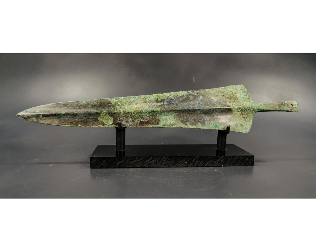 GREEK ARCHAIC PERIOD SWORD BLADE: Ca. 1600 - 1000 BC. Greek Archaic Period Sword Blade. A large and well-formed bronze blade that rises in the center in a very gentle ridge and flattens out at twin sharp edges. A sturdy tang ending in