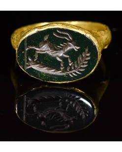 ROMAN GOLD INTAGLIO RING WITH A STAG: CA. 200 AD. Rare Ancient Roman gold ring; a well-preserved hoop forming an elliptical bezel; beautifully carved green intaglio stone inserted in the middle; depicting a standing stag near a tree; the