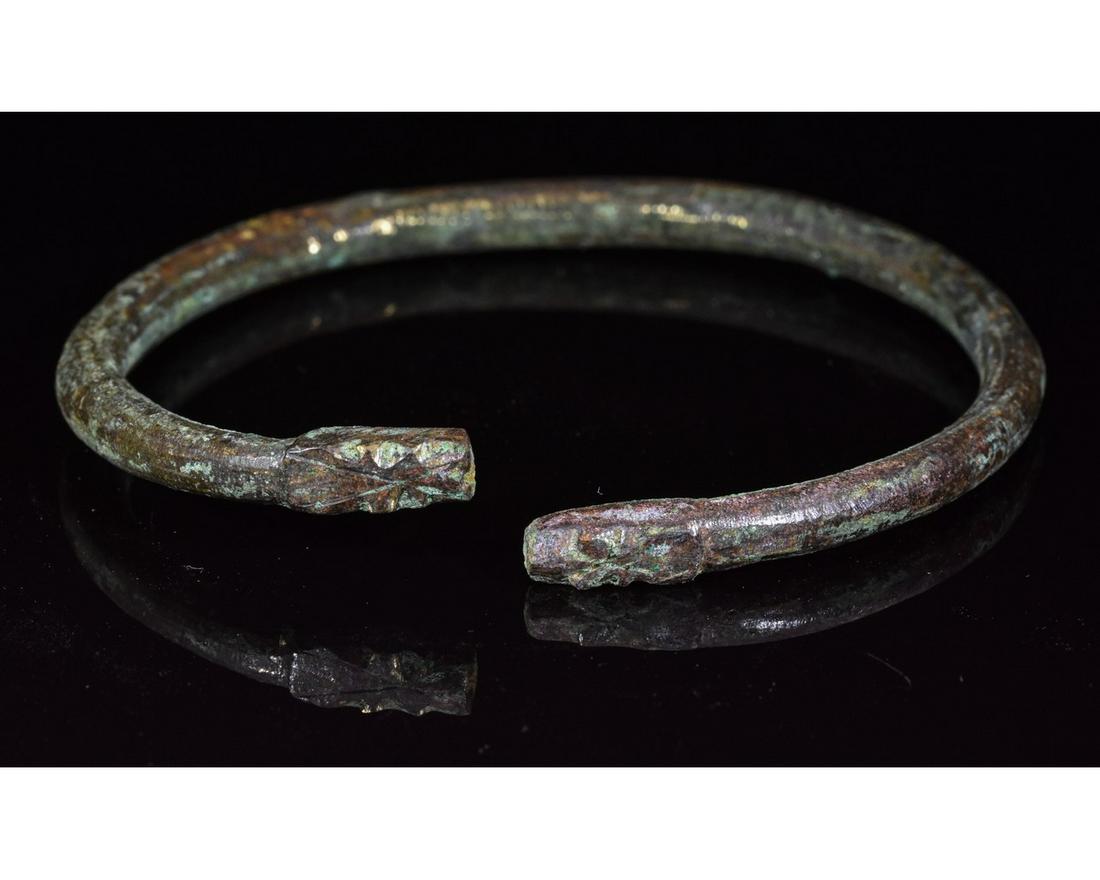 VIKING ERA BRONZE BRACELET WITH WOLF HEADS: Ca.900 AD. A rare Medieval bronze bracelet with balusters and wolf-head finials representing Fenrir; is the most infamous of the many wolves in Norse mythology. His importance for the pre-Christian Sc