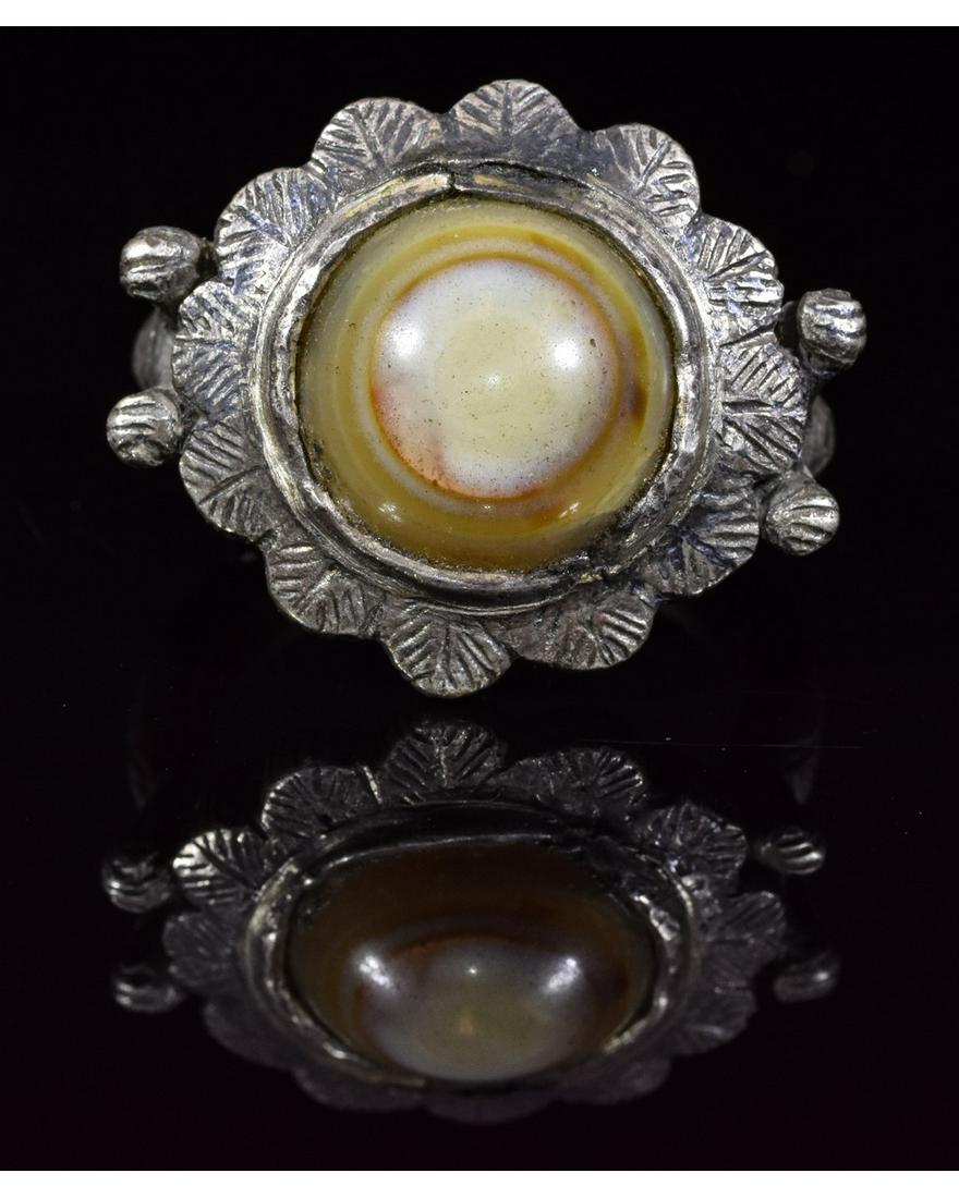 BYZANTINE SILVER RING WITH AGATE EYE STONE: Ca.700-900AD. A carinated broad silver hoop with hexagonal pad to the underside, steep decorated shoulders, rosette bezel, central agate stone inset. Good condition; wearable; D:21mm/L:31mm; UK W US 1