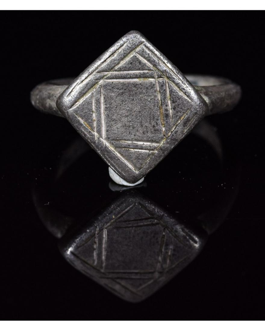 ROMAN SILVER RING WITH GEOMETRIC PATTERN: CA. 100 AD. Interesting Roman ring with applied round hoop and lozenge-shaped bezel; engraved with the unusual geometric pattern; Reference for Roman Rings: Cf. Ruseva-Slokoska, L. Roman Jewellery, So
